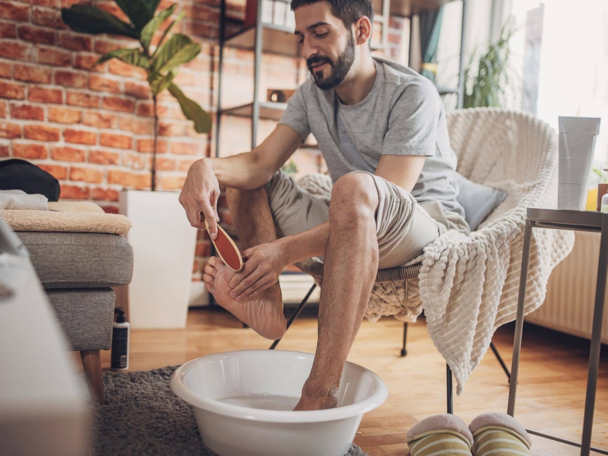 Mann macht ein Fußbett und behandelt eine Nagelbettentzündung mit Hausmitteln.