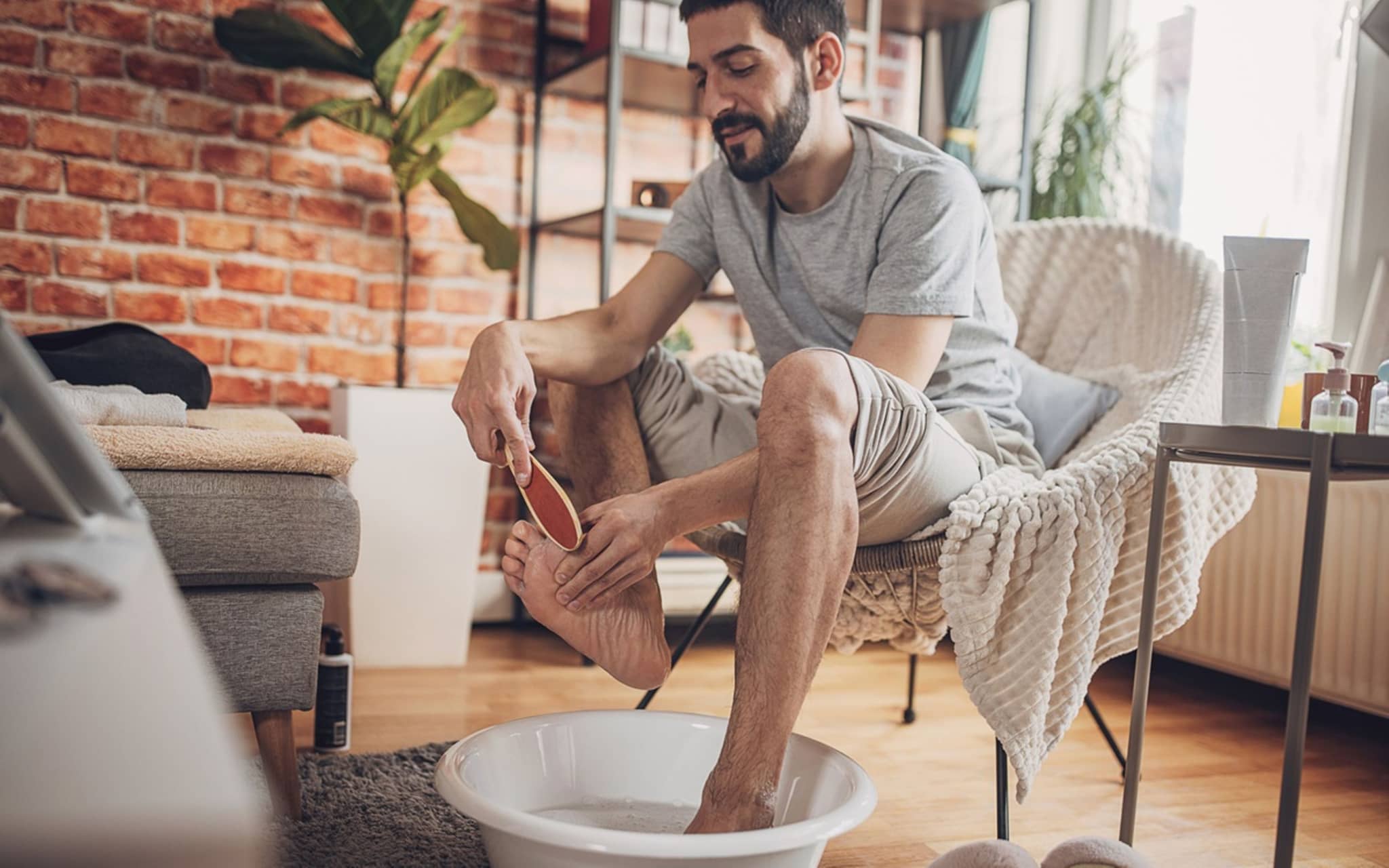 Mann macht ein Fußbett und behandelt eine Nagelbettentzündung mit Hausmitteln.