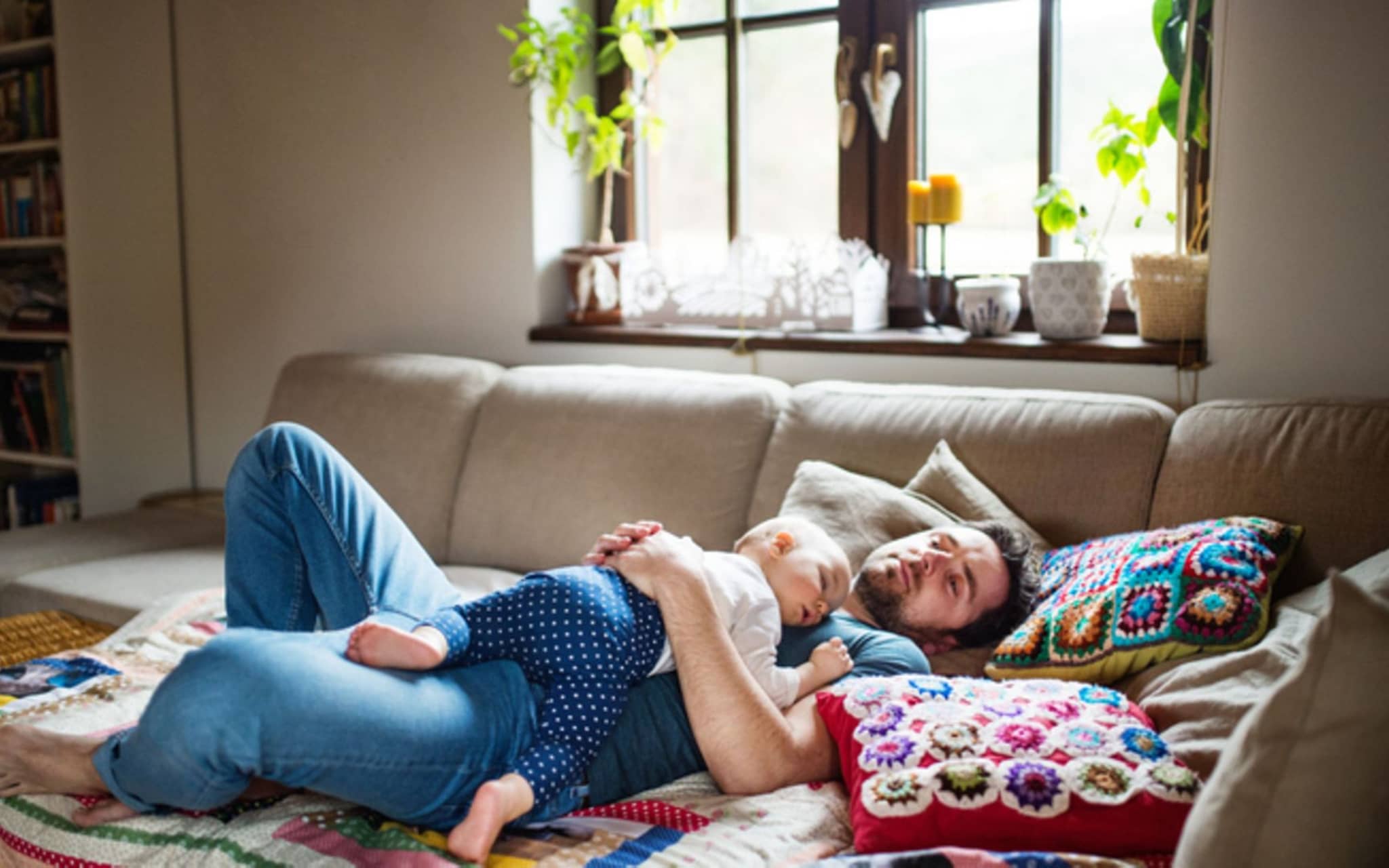 Mittagsschlaf: Vater mit einem kleinen Mädchen zu Hause, das auf dem Sofa schläft.