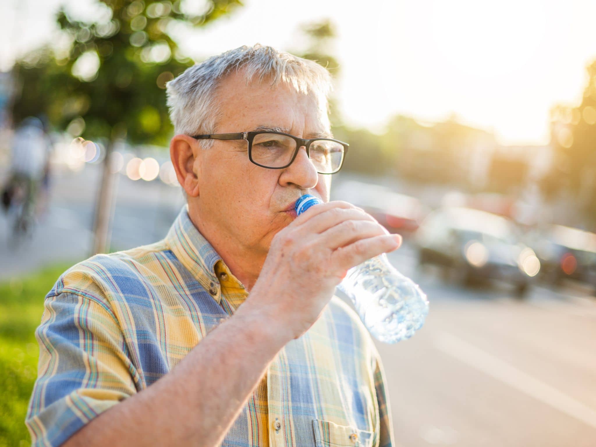 Bild: Ein älterer Mann trinkt Wasser, um keine Kreislaufprobleme bei Hitze zu bekommen.