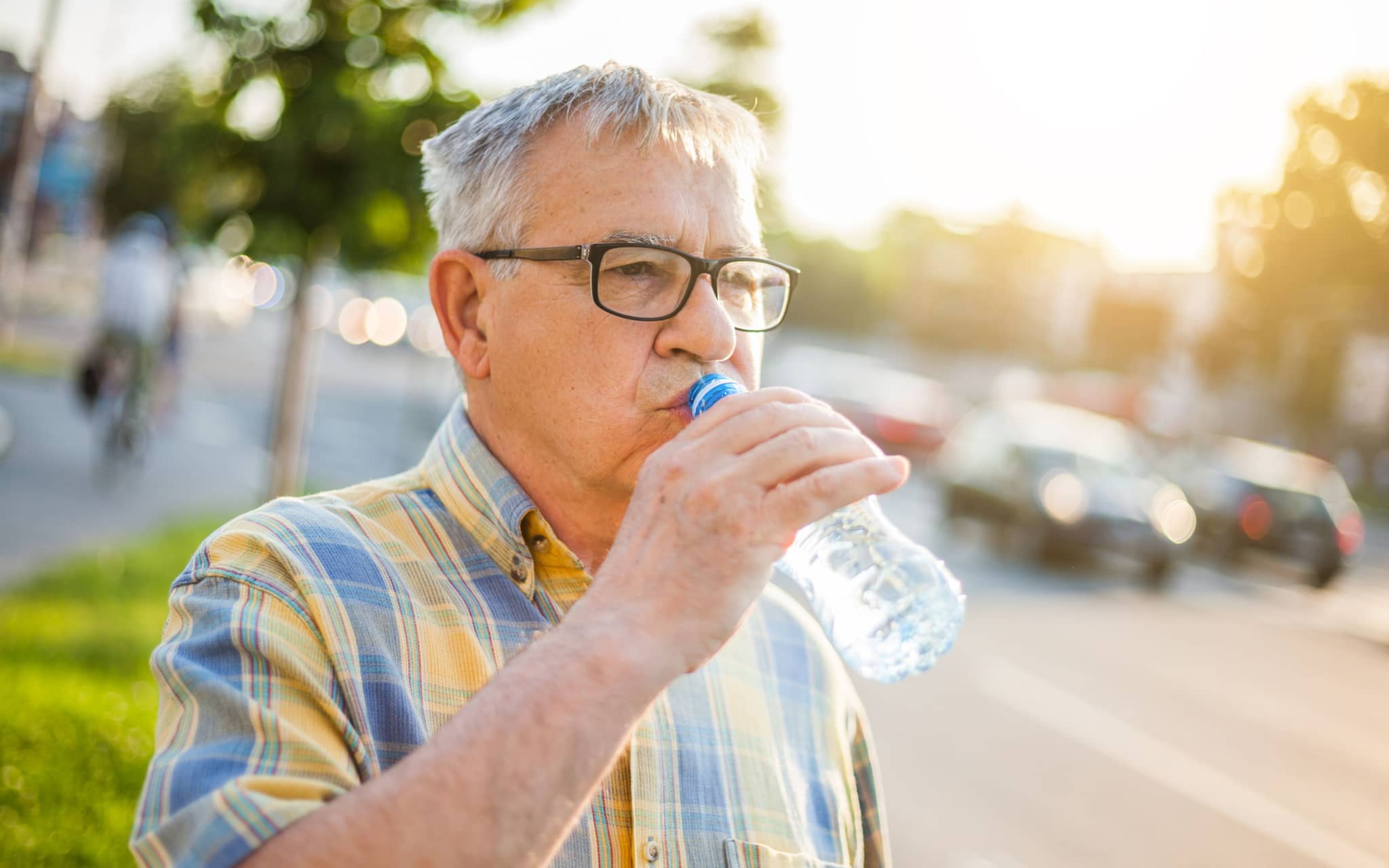 Bild: Ein älterer Mann trinkt Wasser, um keine Kreislaufprobleme bei Hitze zu bekommen.