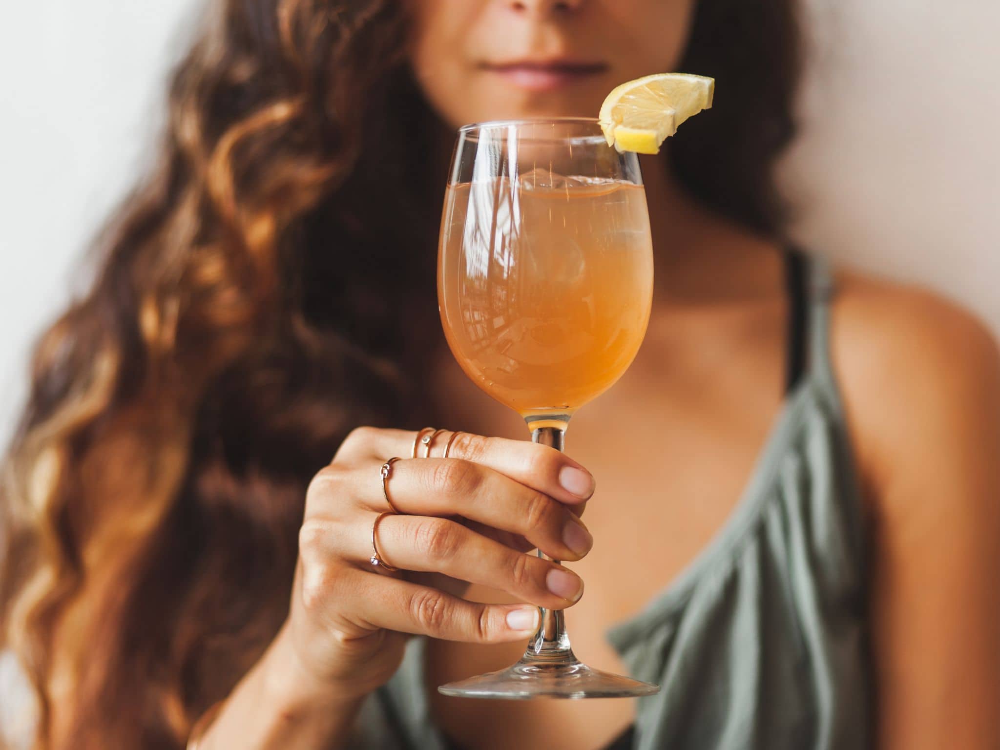 Eine junge Frau hält ein Glas Kombucha in der Hand.