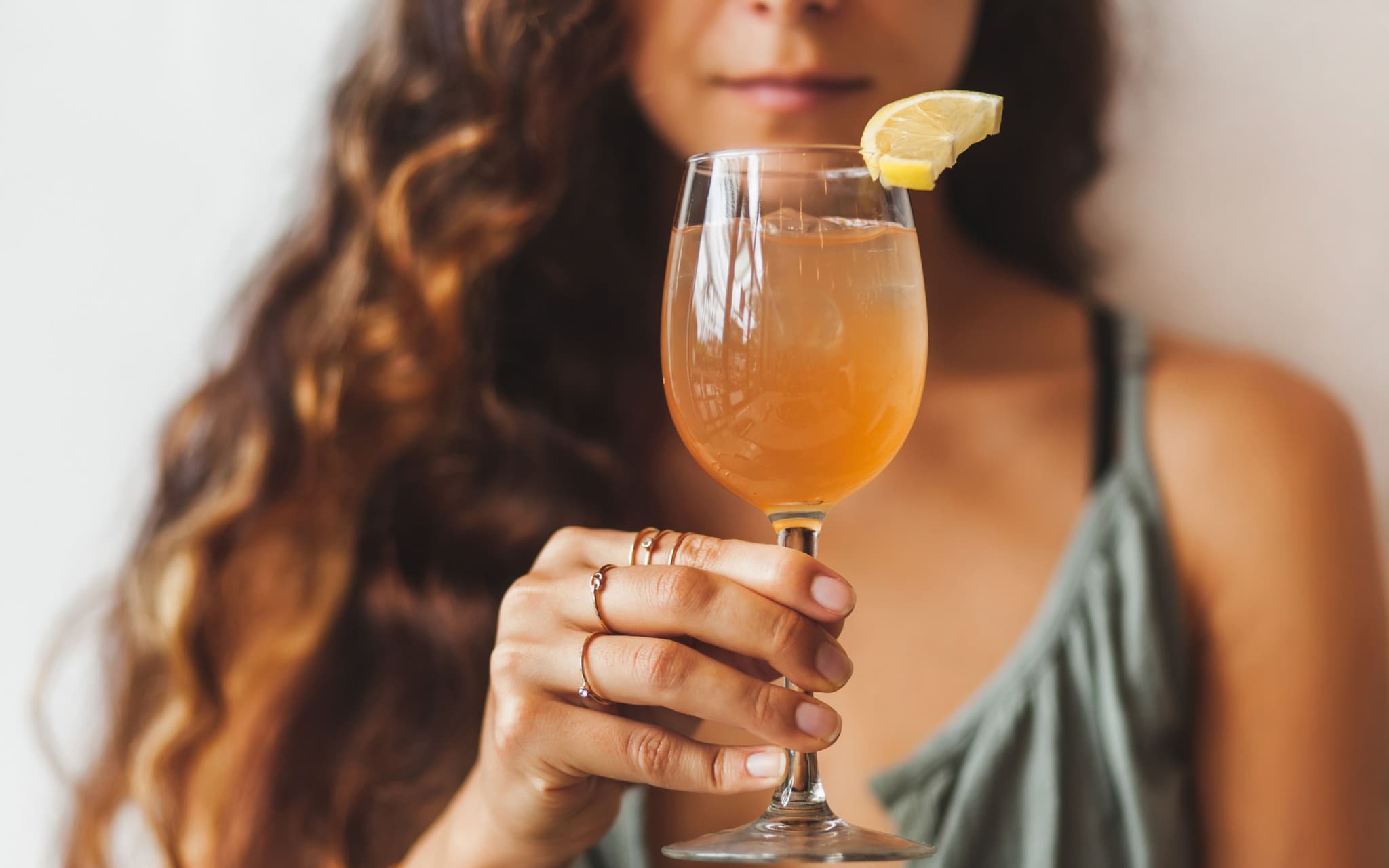Eine junge Frau hält ein Glas Kombucha in der Hand.