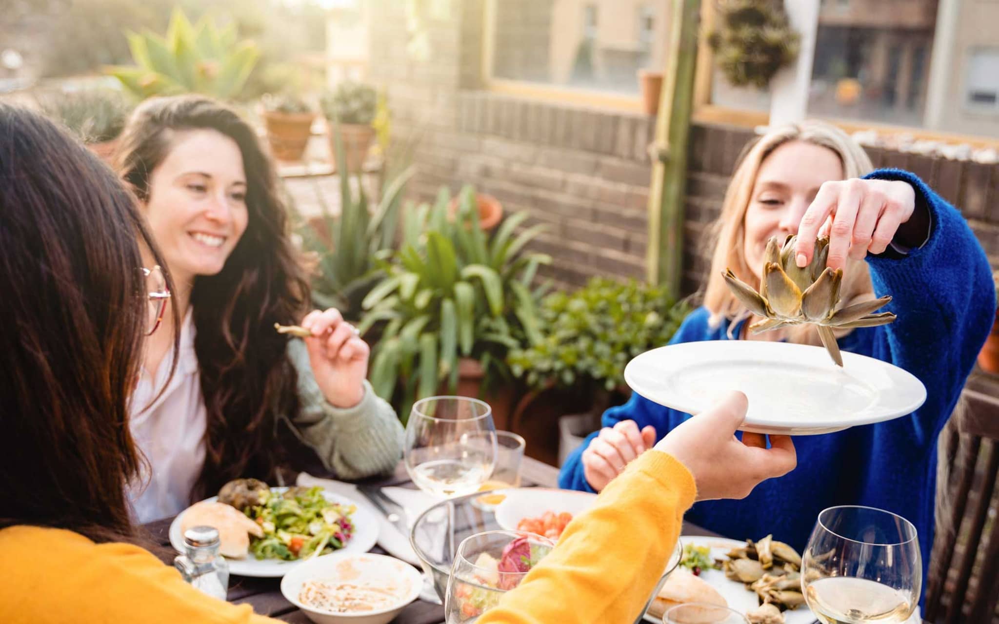 Frau greift zur Artischocke, in der Bitterstoffe stecken