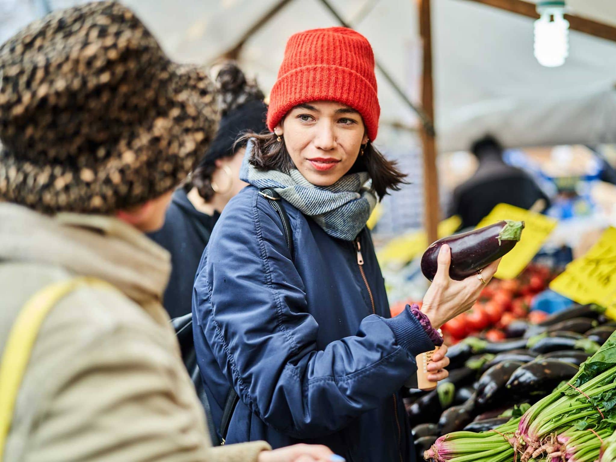 Zwei Freundinnen kaufen Gemüse auf dem Wochenmarkt