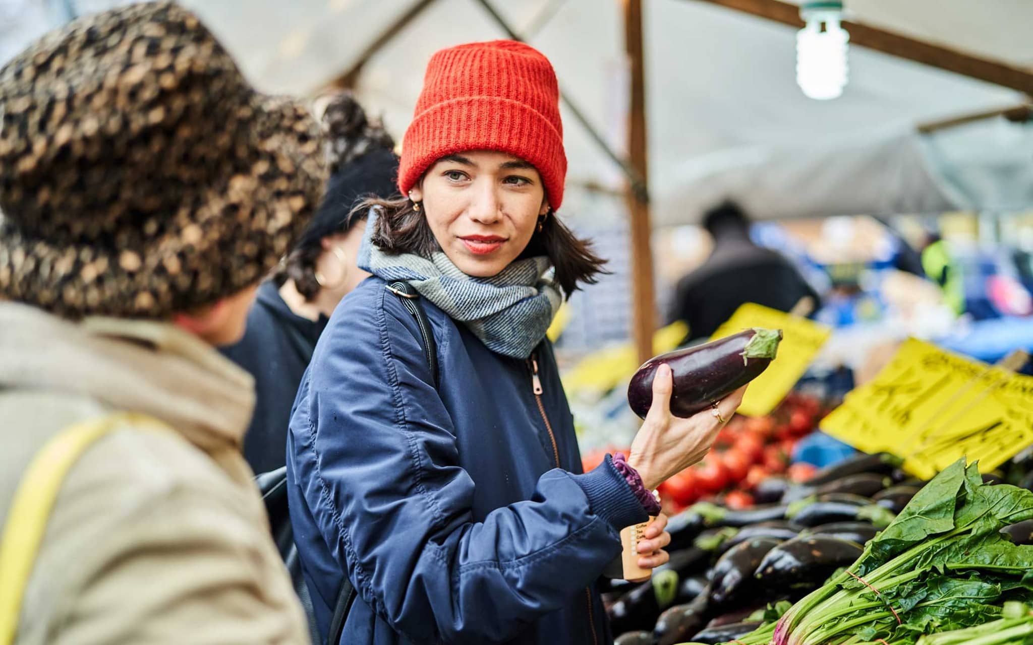 Zwei Freundinnen kaufen Gemüse auf dem Wochenmarkt