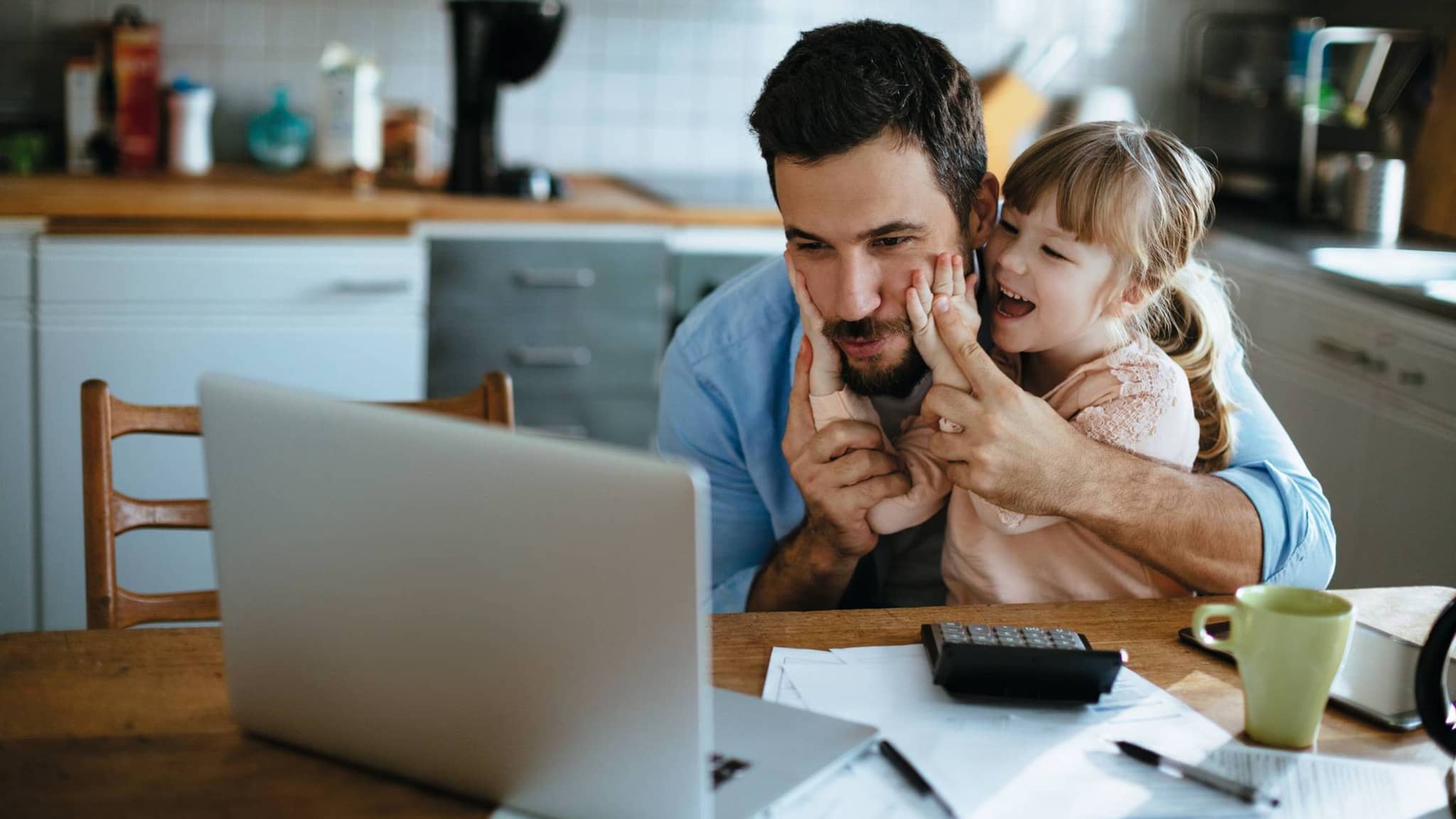 Ein Vater und seine Tochter informieren sich am Laptop über die Familienversicherung.