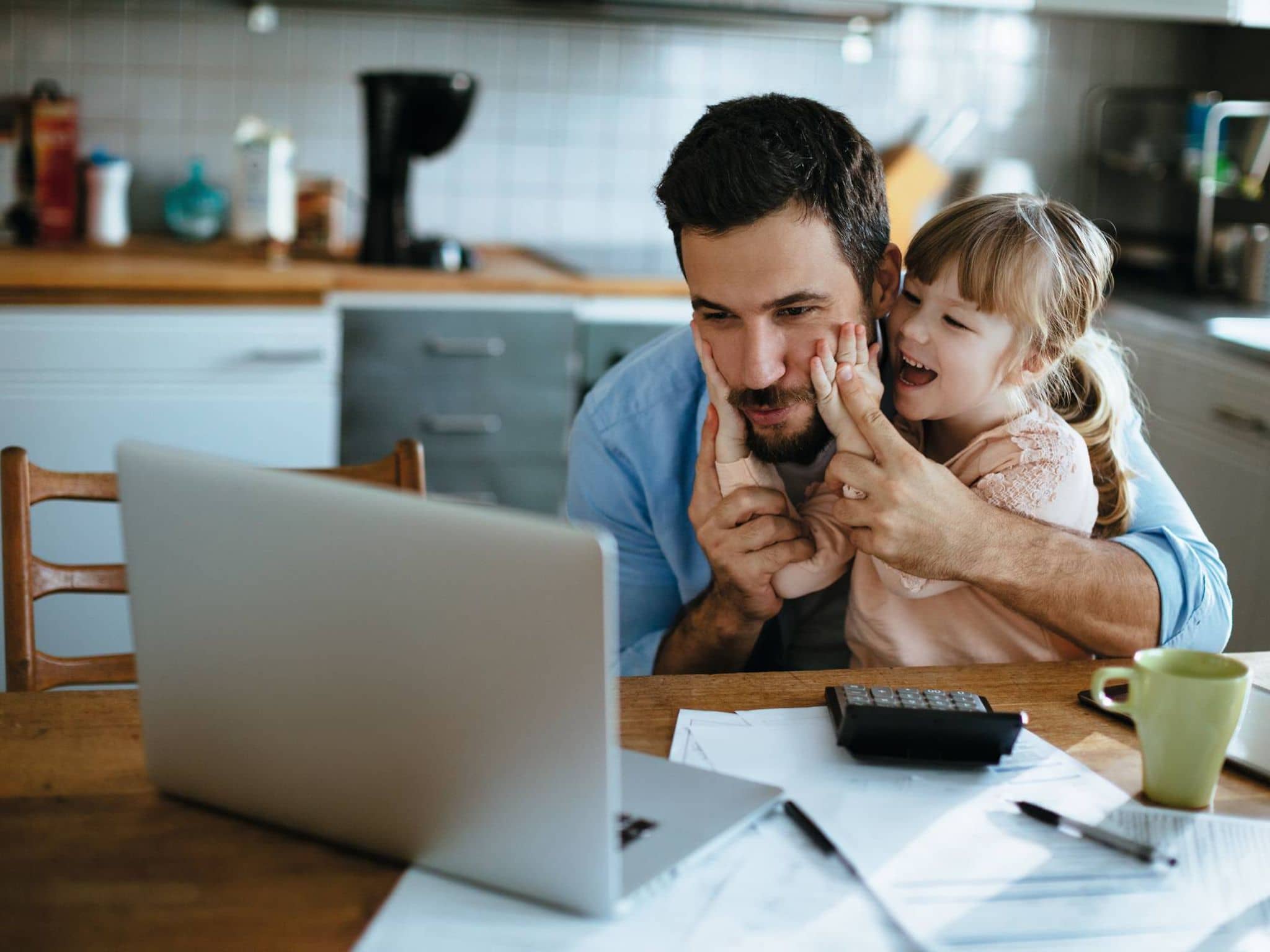 Ein Vater und seine Tochter informieren sich am Laptop über die Familienversicherung.