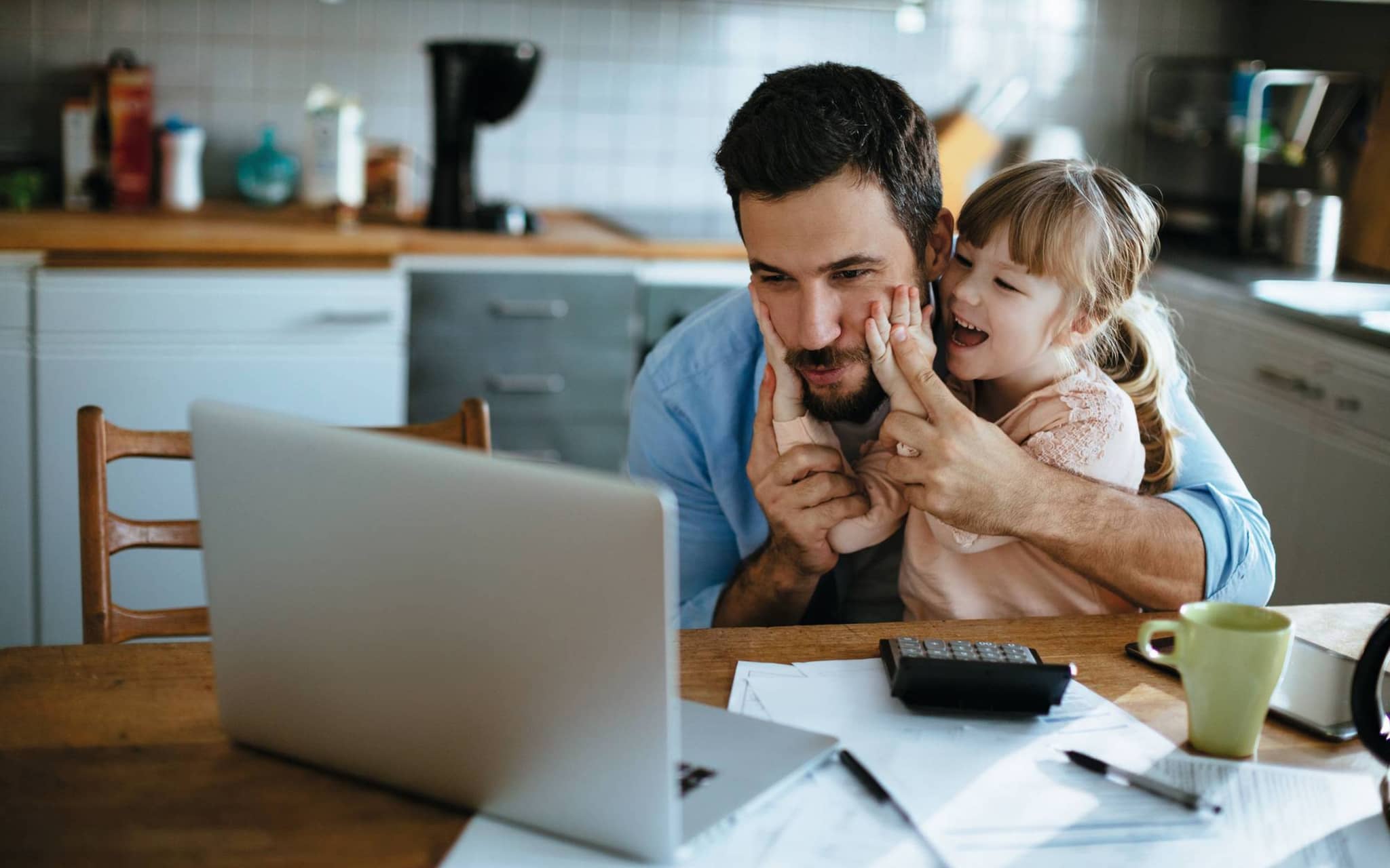 Ein Vater und seine Tochter informieren sich am Laptop über die Familienversicherung.
