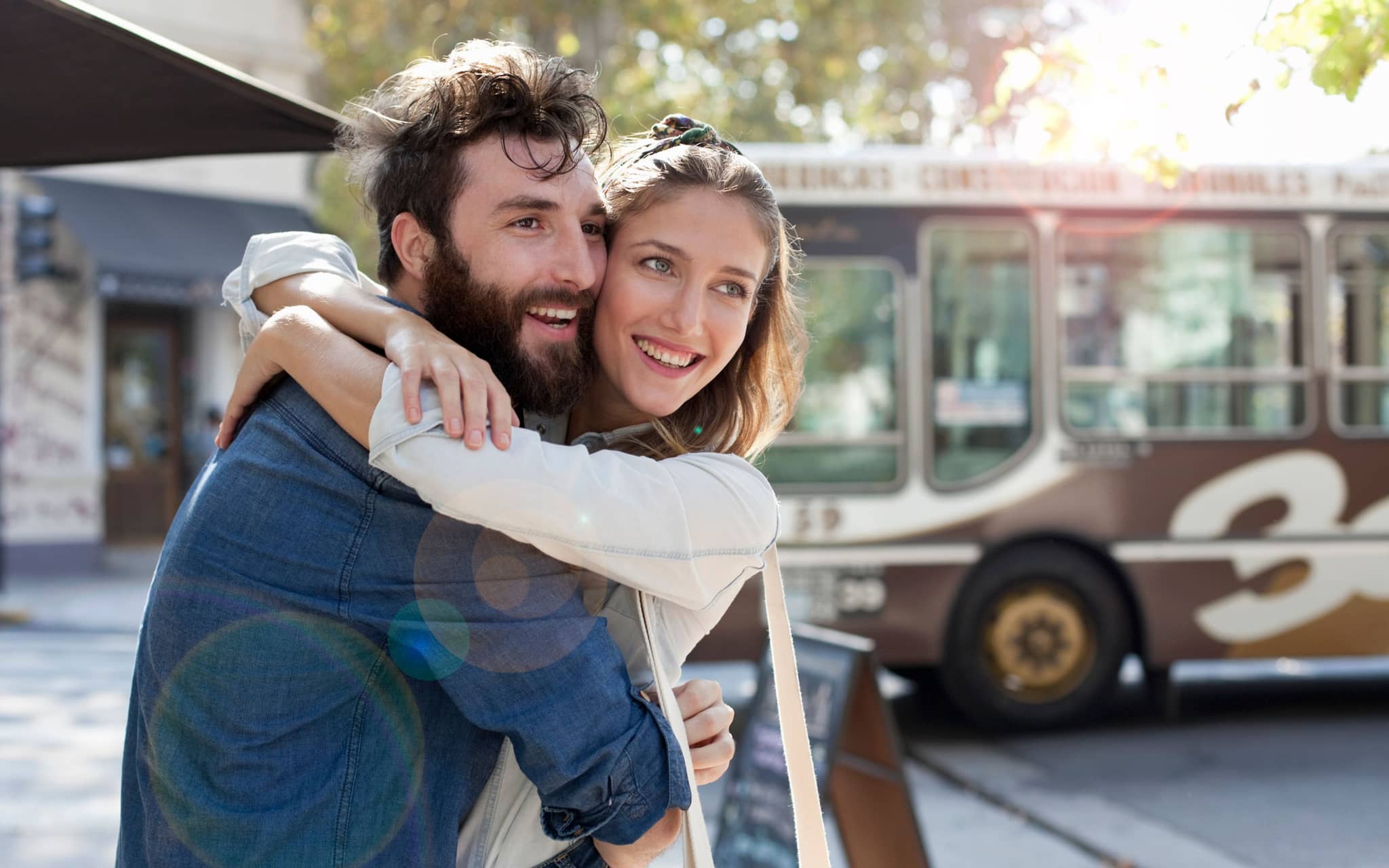 Symbolbild Vorhaut: Ein junge Mann nimmt eine junge Frau von hinten in den Arm und lächelt
