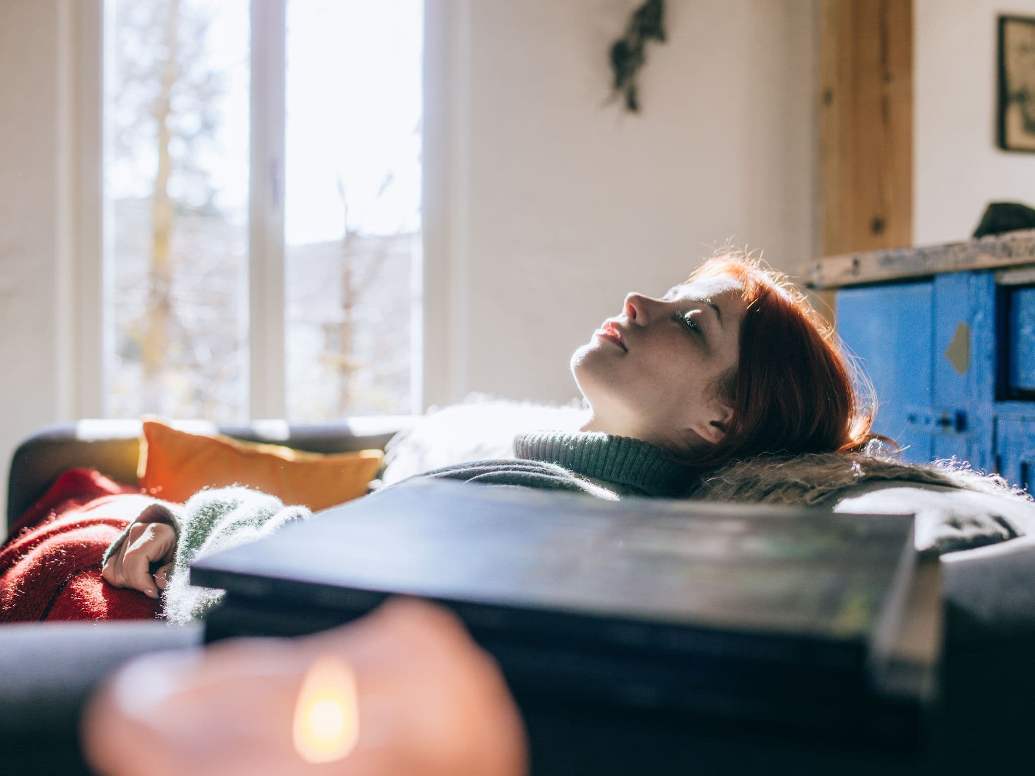 Junge Frau liegt auf dem Sofa und gönnt sich einen Powernap.