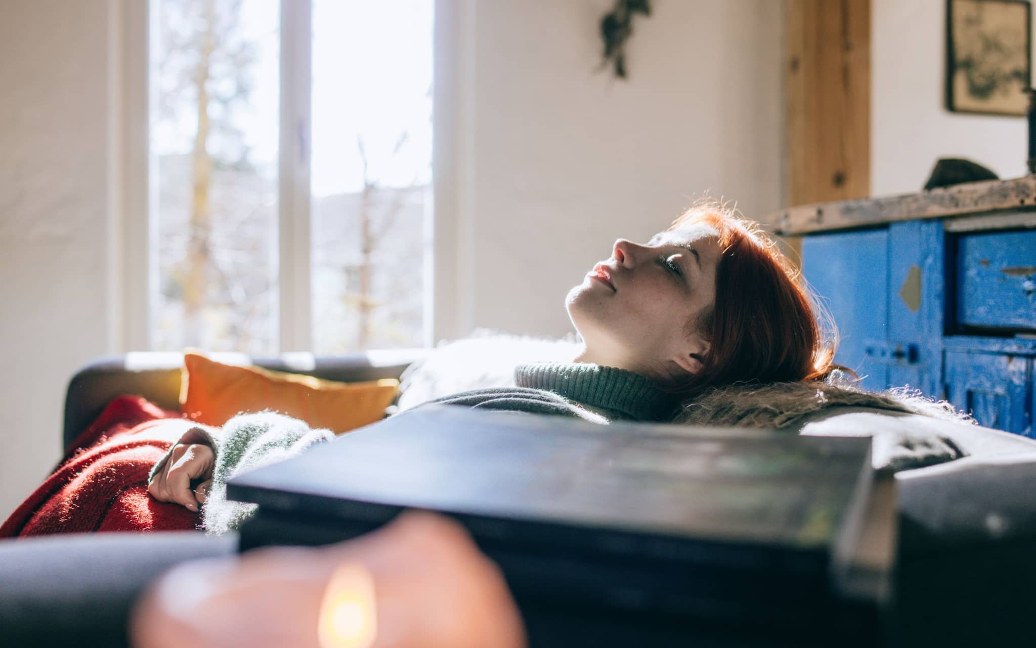 Junge Frau liegt auf dem Sofa und gönnt sich einen Powernap.
