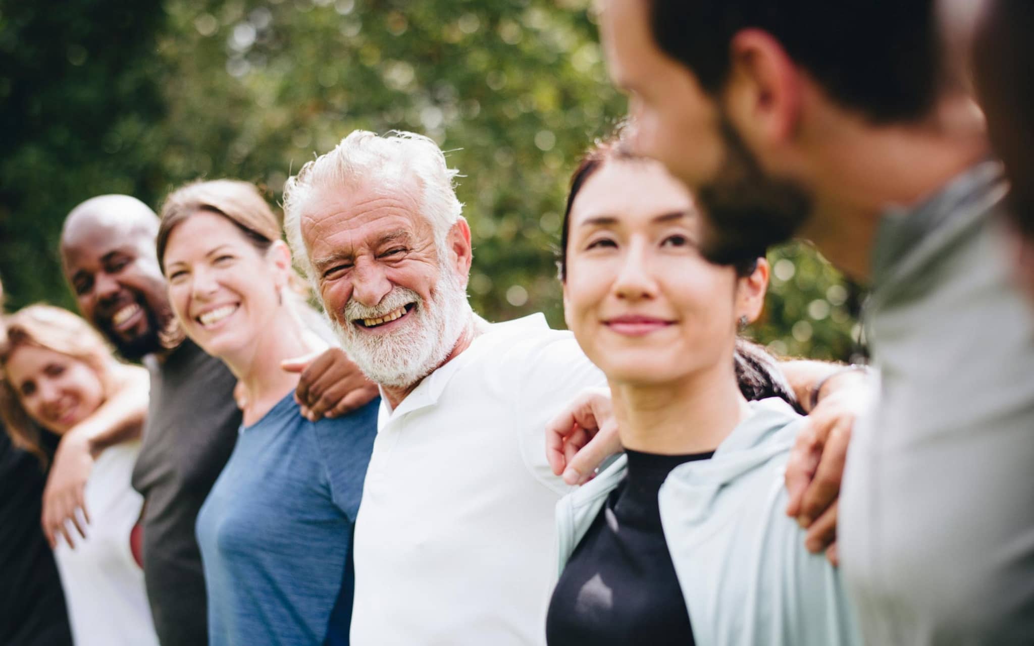 Nachhaltigkeit: Eine Kette von fröhlichen Menschen, die sich umarmen.