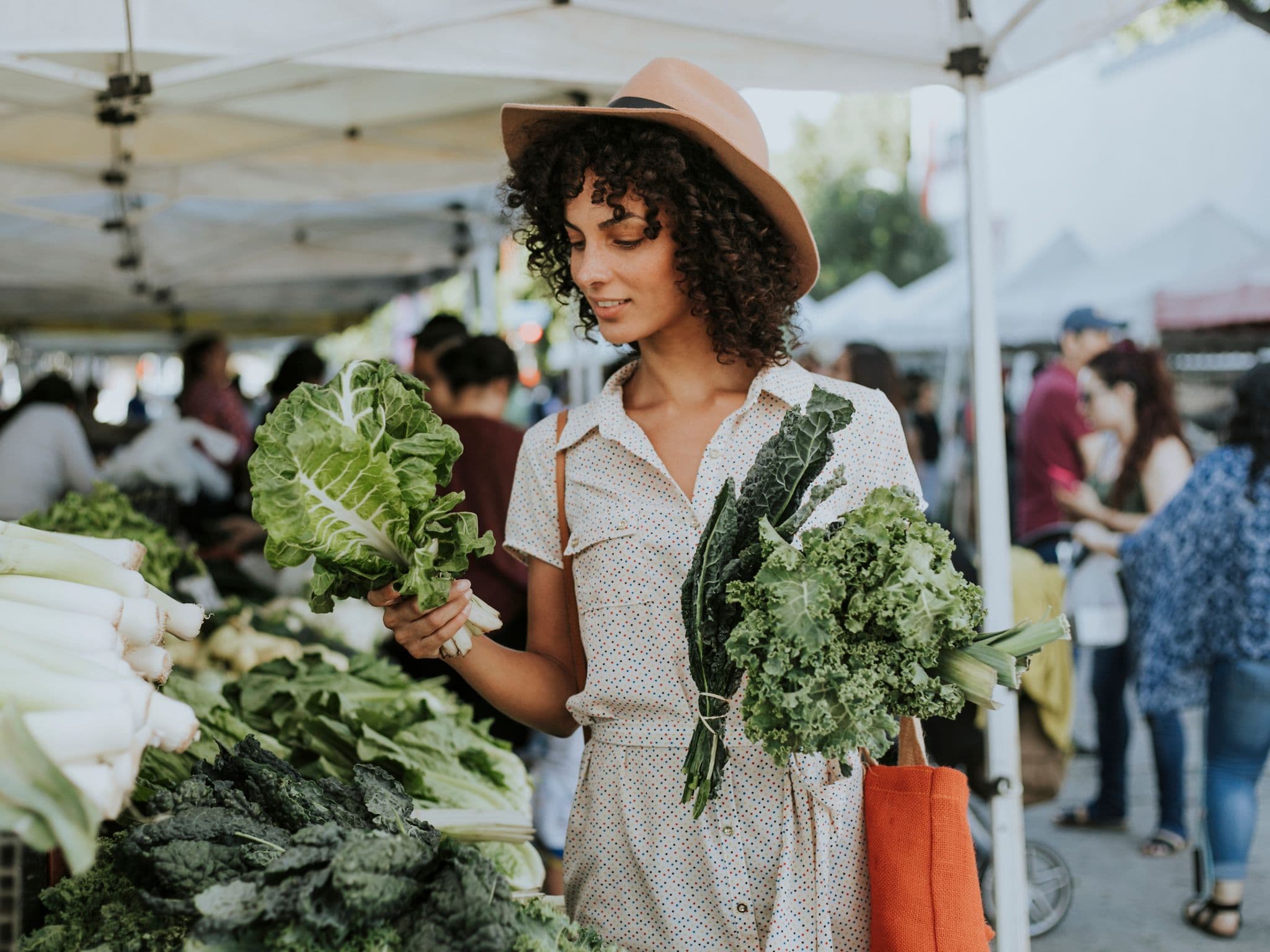 Frau kauft auf dem Wochenmarkt grünes Gemüse ein, um eine Fettleber vorzubeugen.