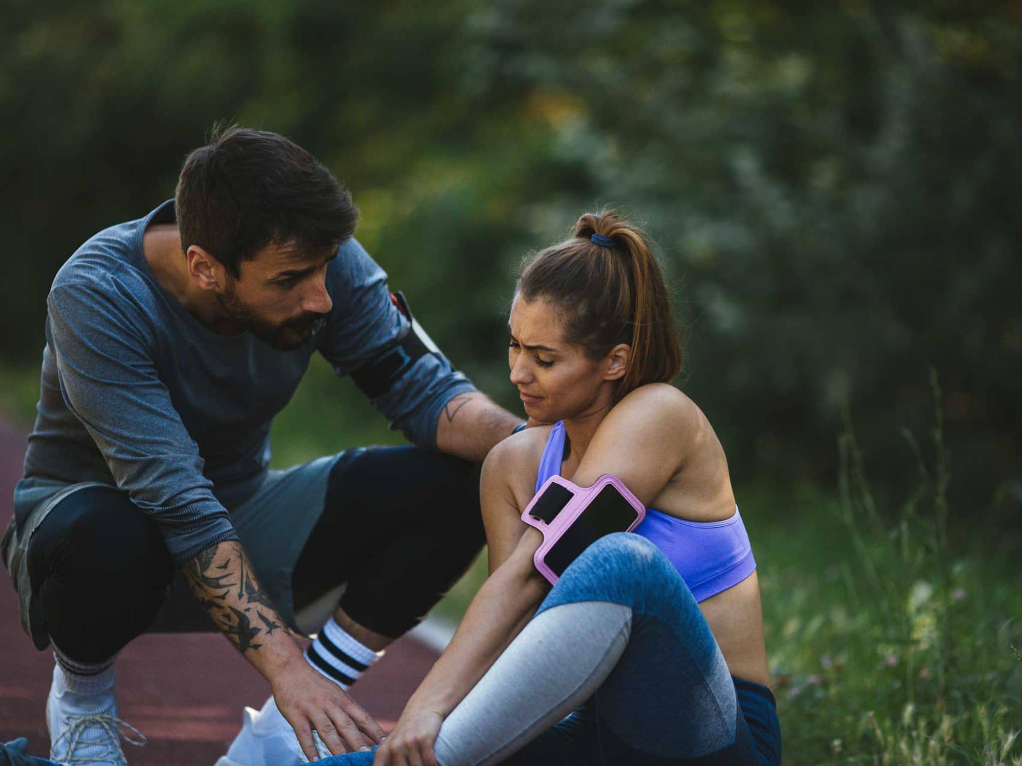 Mann kümmert sich um Frau, die sich beim Laufen verletzt hat