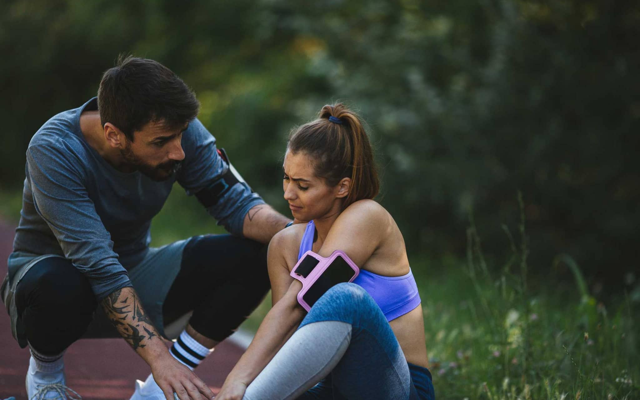 Mann kümmert sich um Frau, die sich beim Laufen verletzt hat