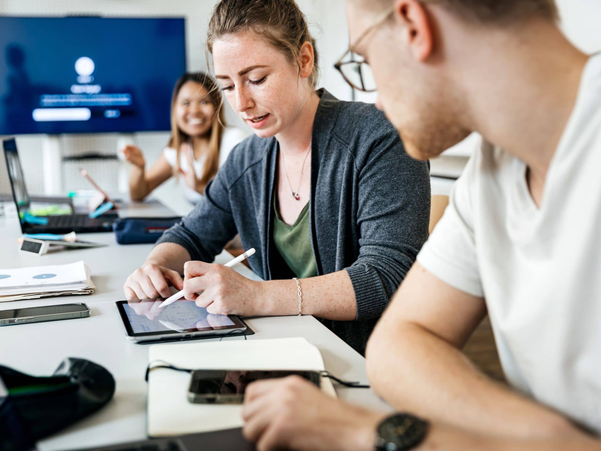 Bildungsurlaub: Junge Frau zeigt Mann im Seminarraum etwas auf einem Tablet.