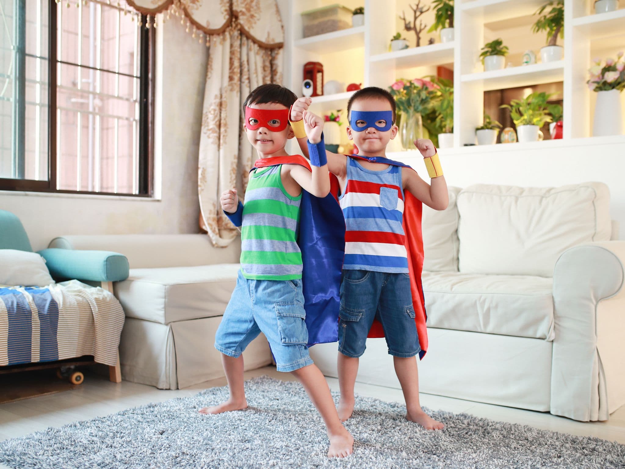 Indoor-Spiele: Zwei kleine verkleidete Jungs in einem Wohnzimmer.