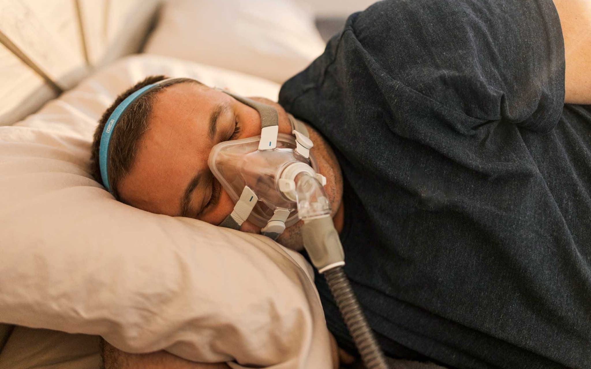 Mann schläft mit CPAP-Gerät