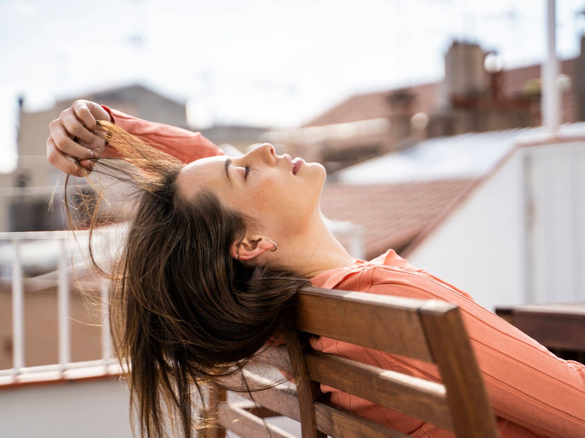 Junge Frau tankt auf dem Dach Sonne, um Vitamin-D-Mangel vorzubeugen.