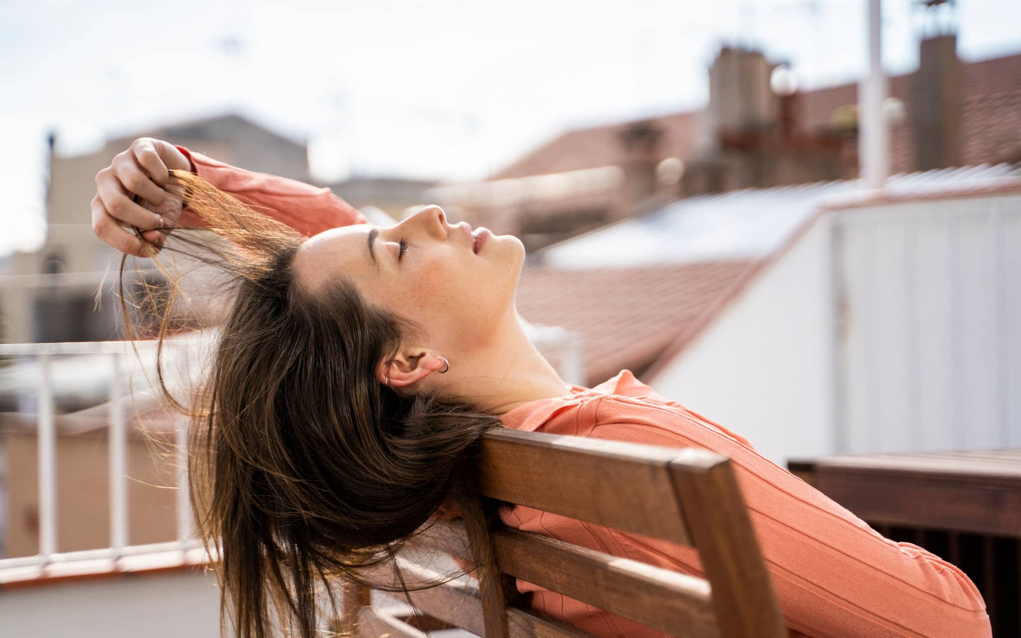 Junge Frau tankt auf dem Dach Sonne, um Vitamin-D-Mangel vorzubeugen.