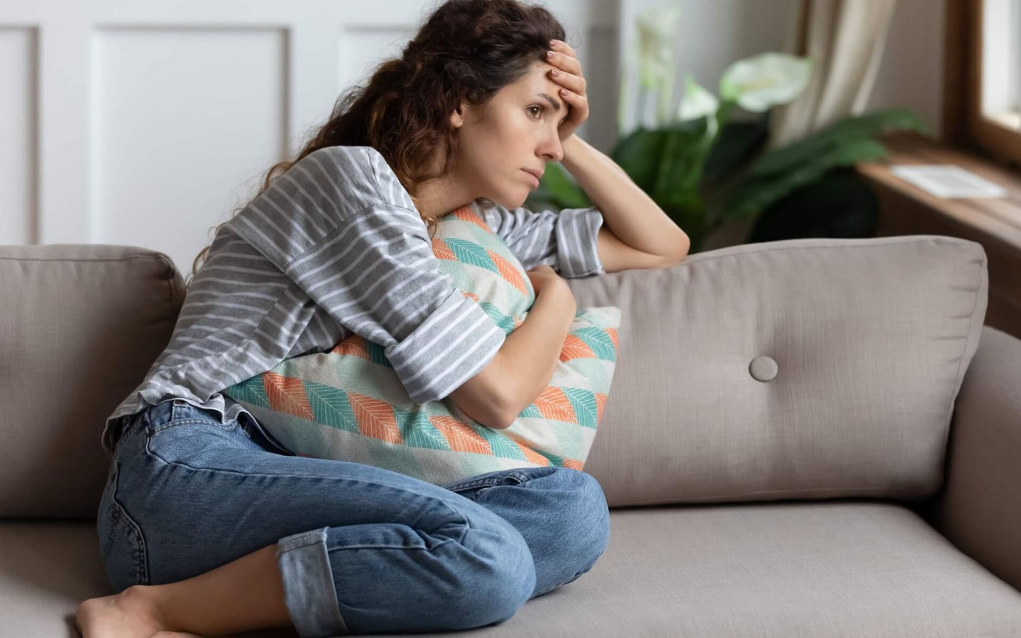 Frau sitzt erschöpft auf dem Sofa und starrt ins Leere