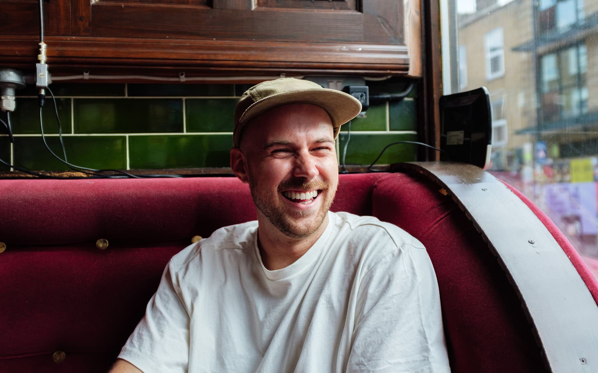 Penis stimulieren: Ein junger Mann sitzt auf einem Sofa und lächelt zufrieden