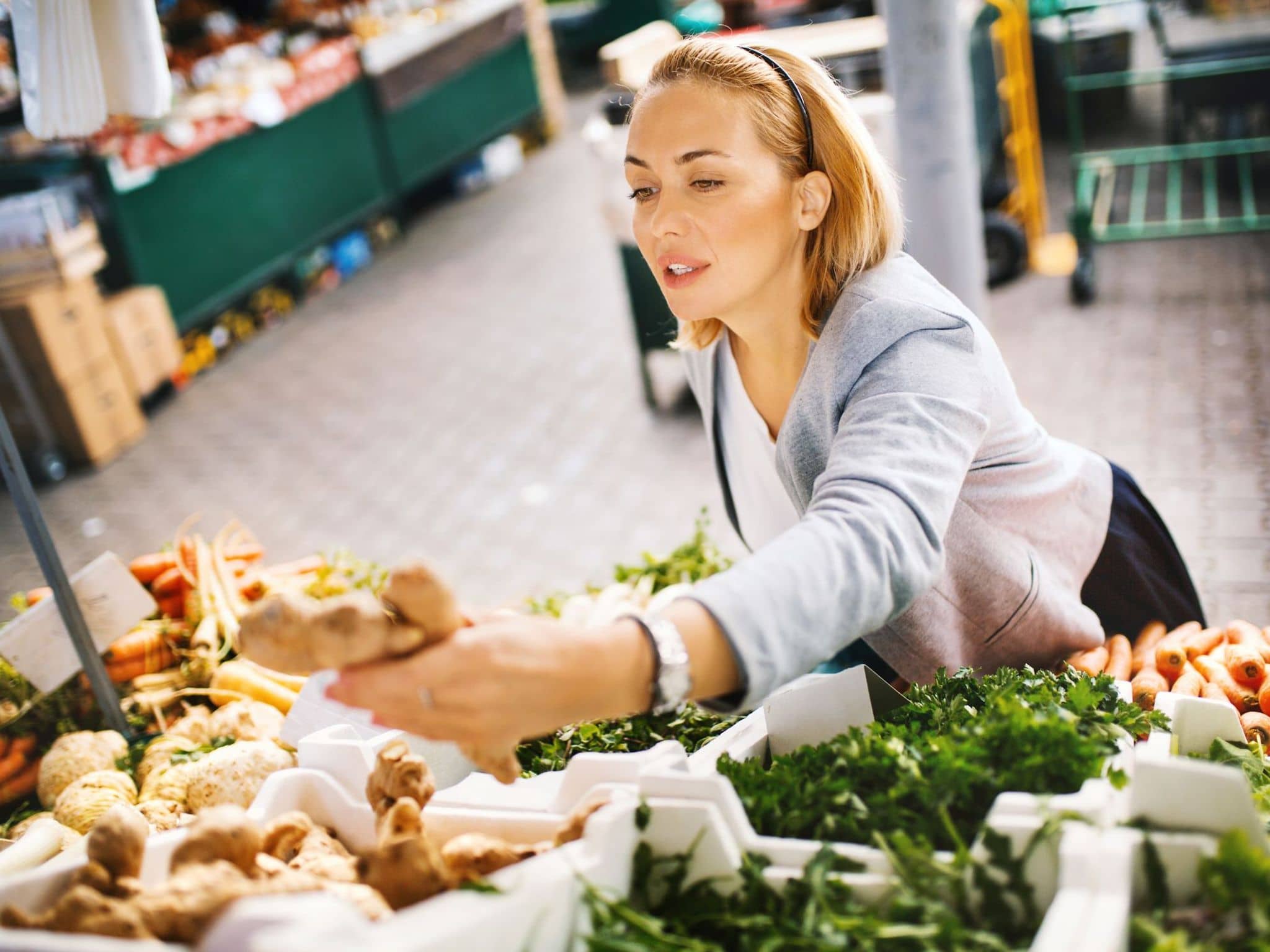 Für einen Ingwer Shot kauft eine Frau frischen Ingwer auf dem Markt.