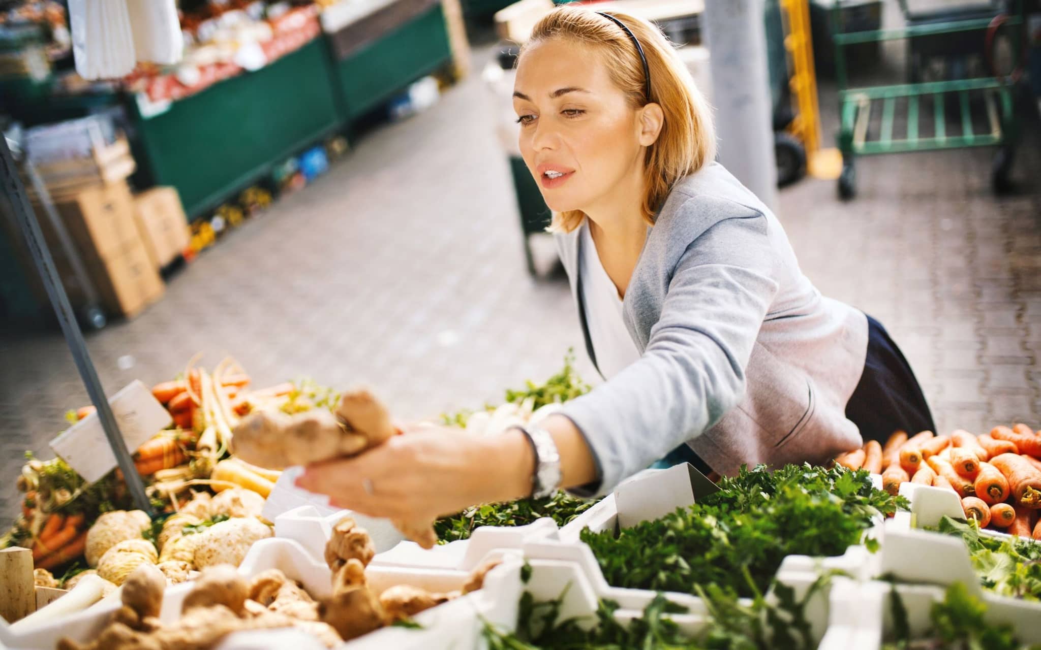Für einen Ingwer Shot kauft eine Frau frischen Ingwer auf dem Markt.