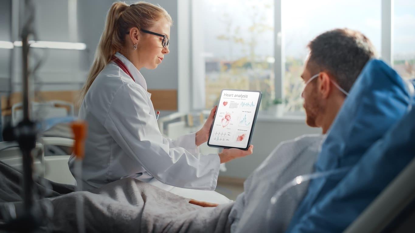 Krankenhausbehandlung in einer Privatklinik: Ärztin und Patient schauen gemeinsam auf ein Tablet. 