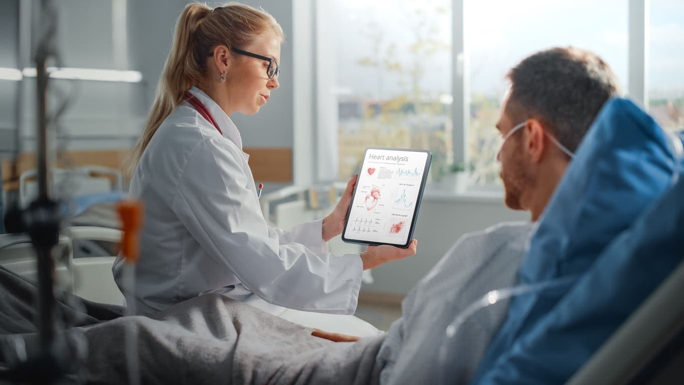 Krankenhausbehandlung in einer Privatklinik: Ärztin und Patient schauen gemeinsam auf ein Tablet.