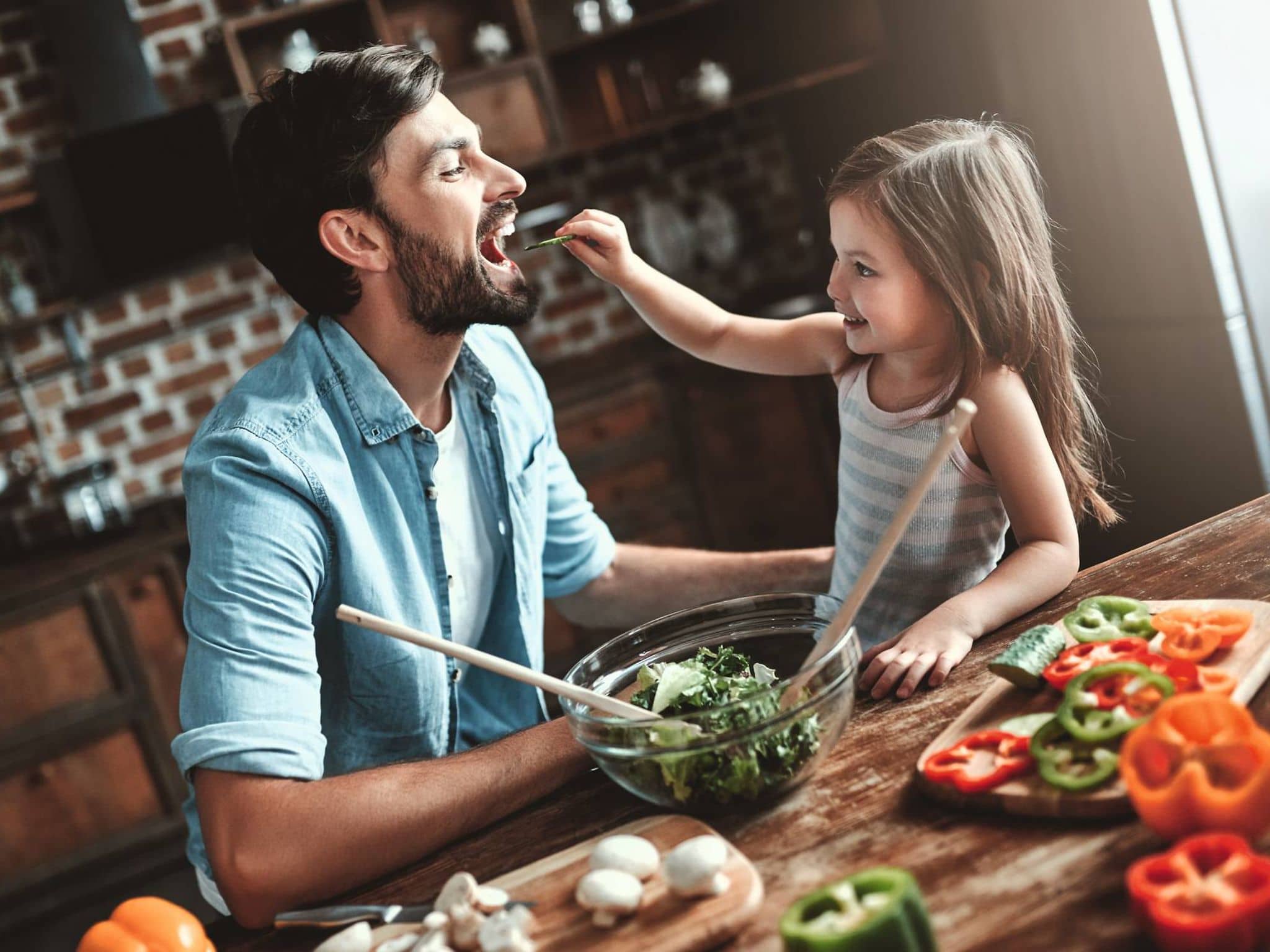 Ein Vater und seine Tochter schnippeln Gemüse für eine gesunde Mahlzeit.