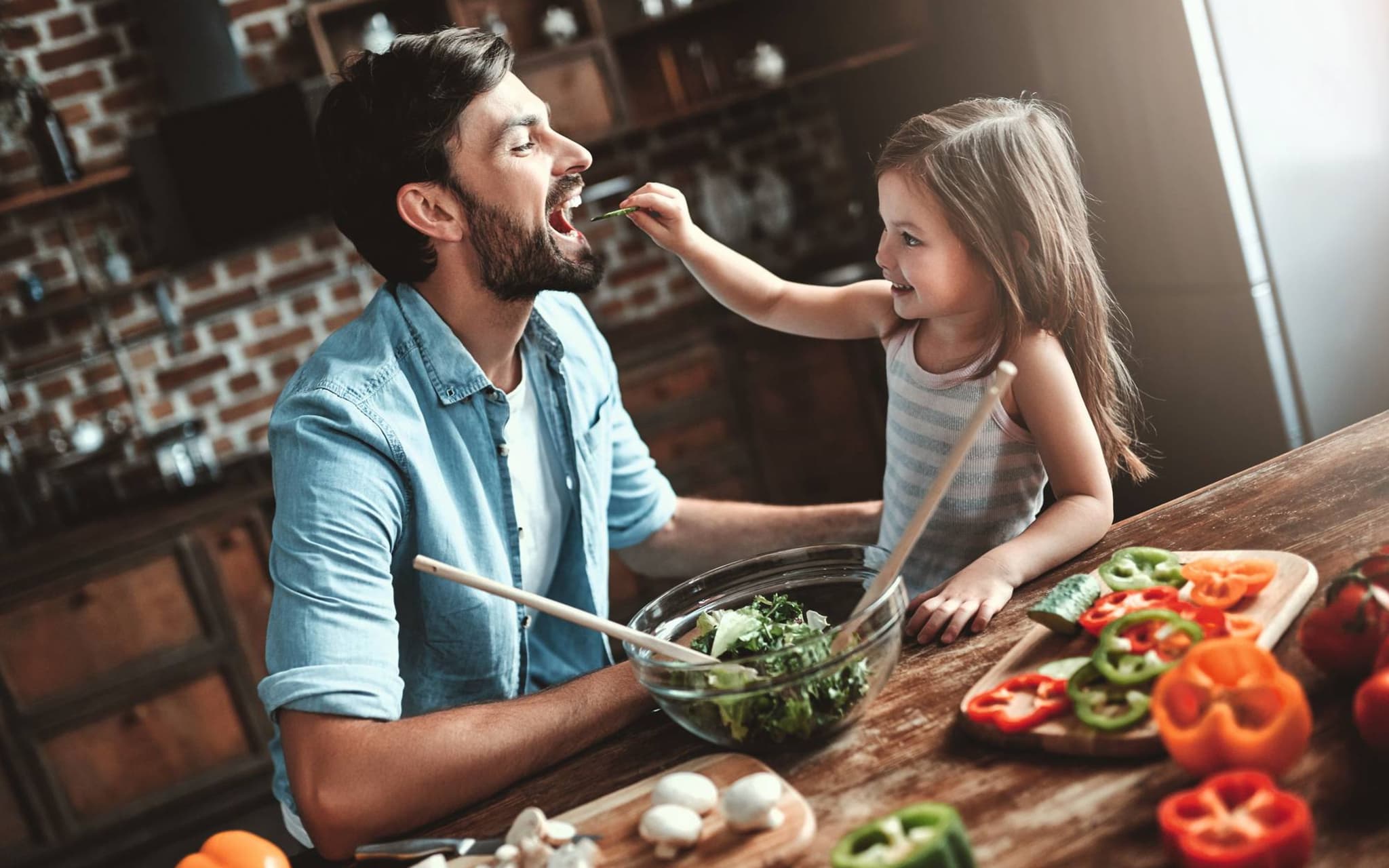 Ein Vater und seine Tochter schnippeln Gemüse für eine gesunde Mahlzeit.