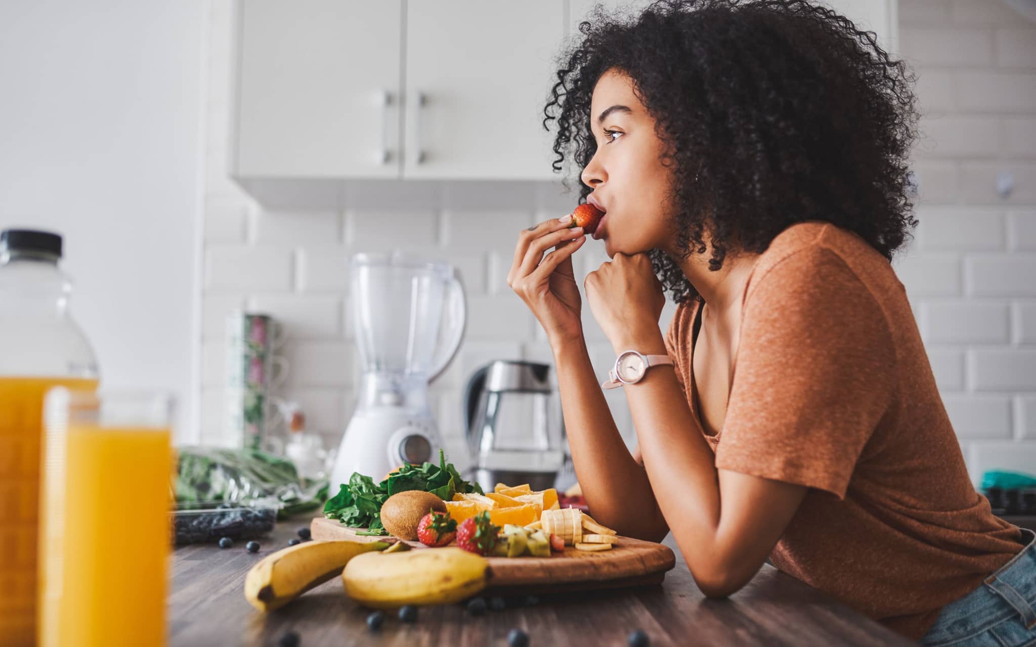 Eine Frau gönnt sich ein gesundes Frühstück bestehend aus viel Gemüse und Obst.