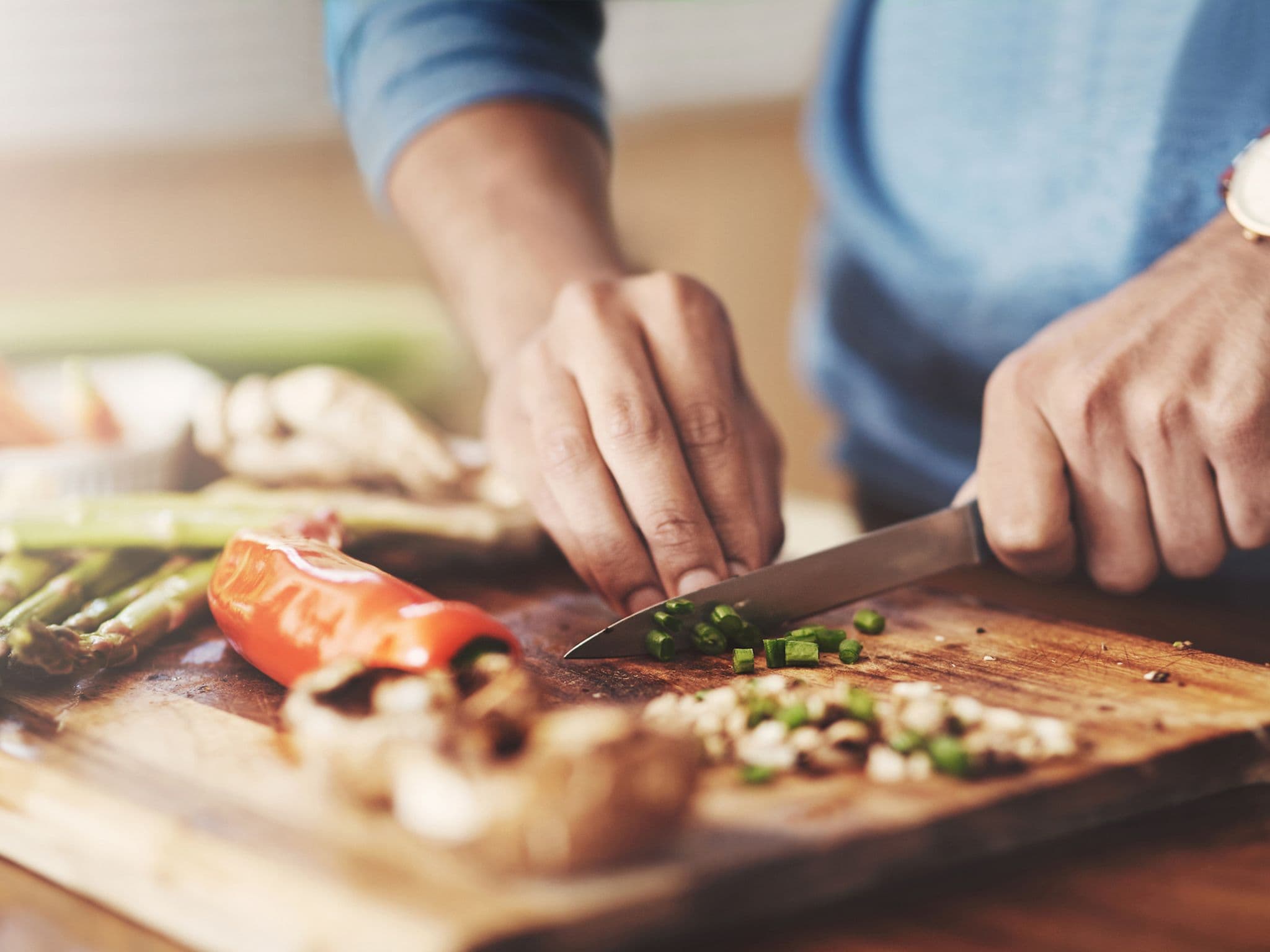 Mann schneidet Gemüse auf Holzbrett