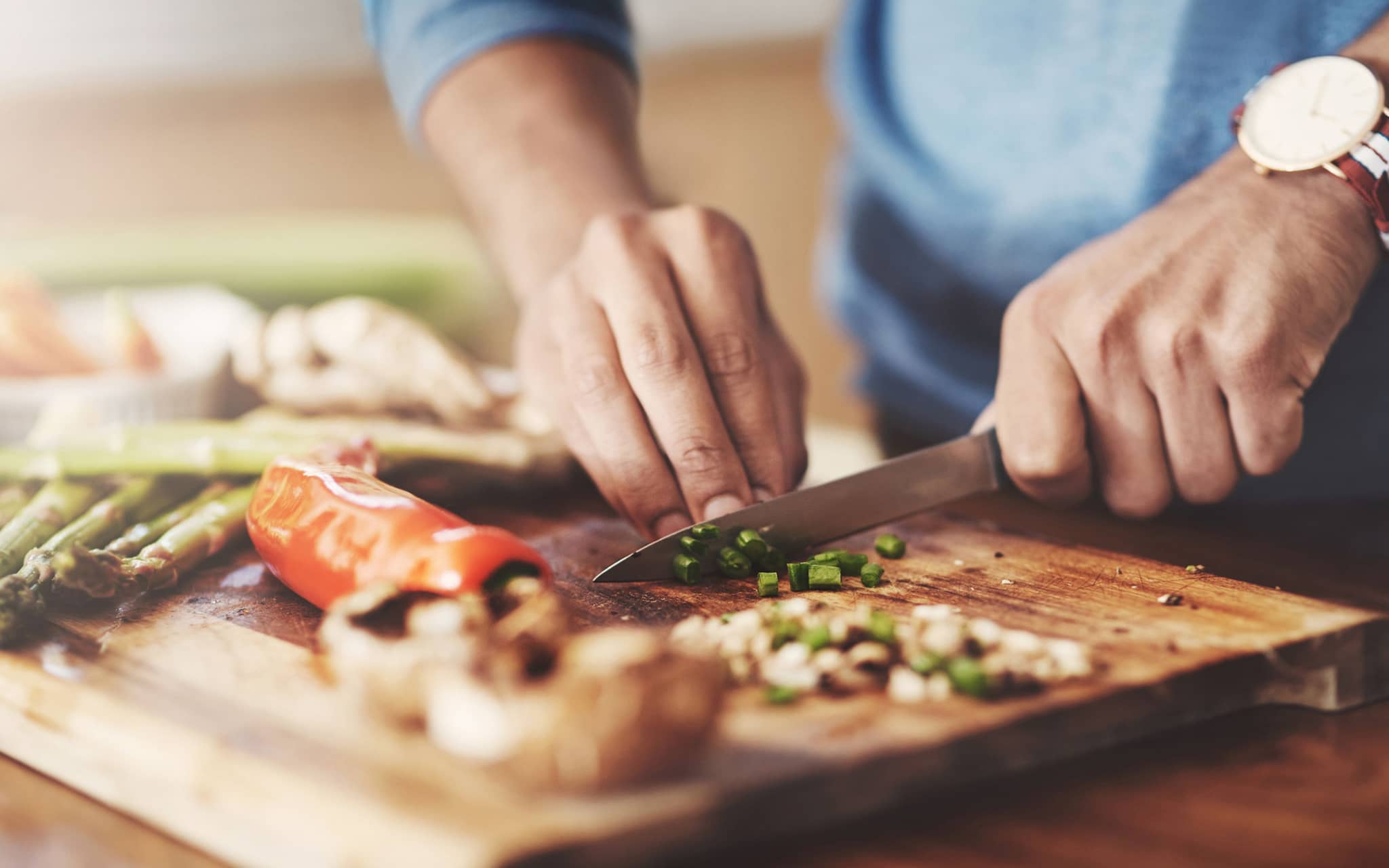 Mann schneidet Gemüse auf Holzbrett