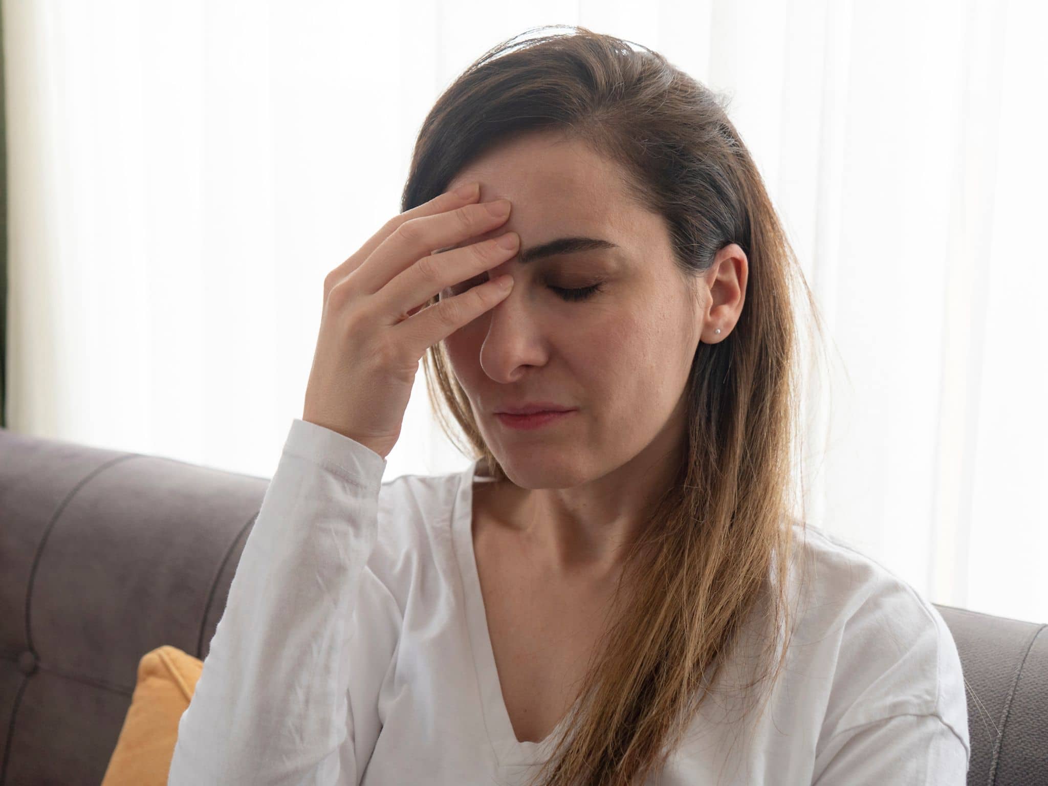 Eine Frau erleidet eine Migräneattacke und greift sich an den Kopf.