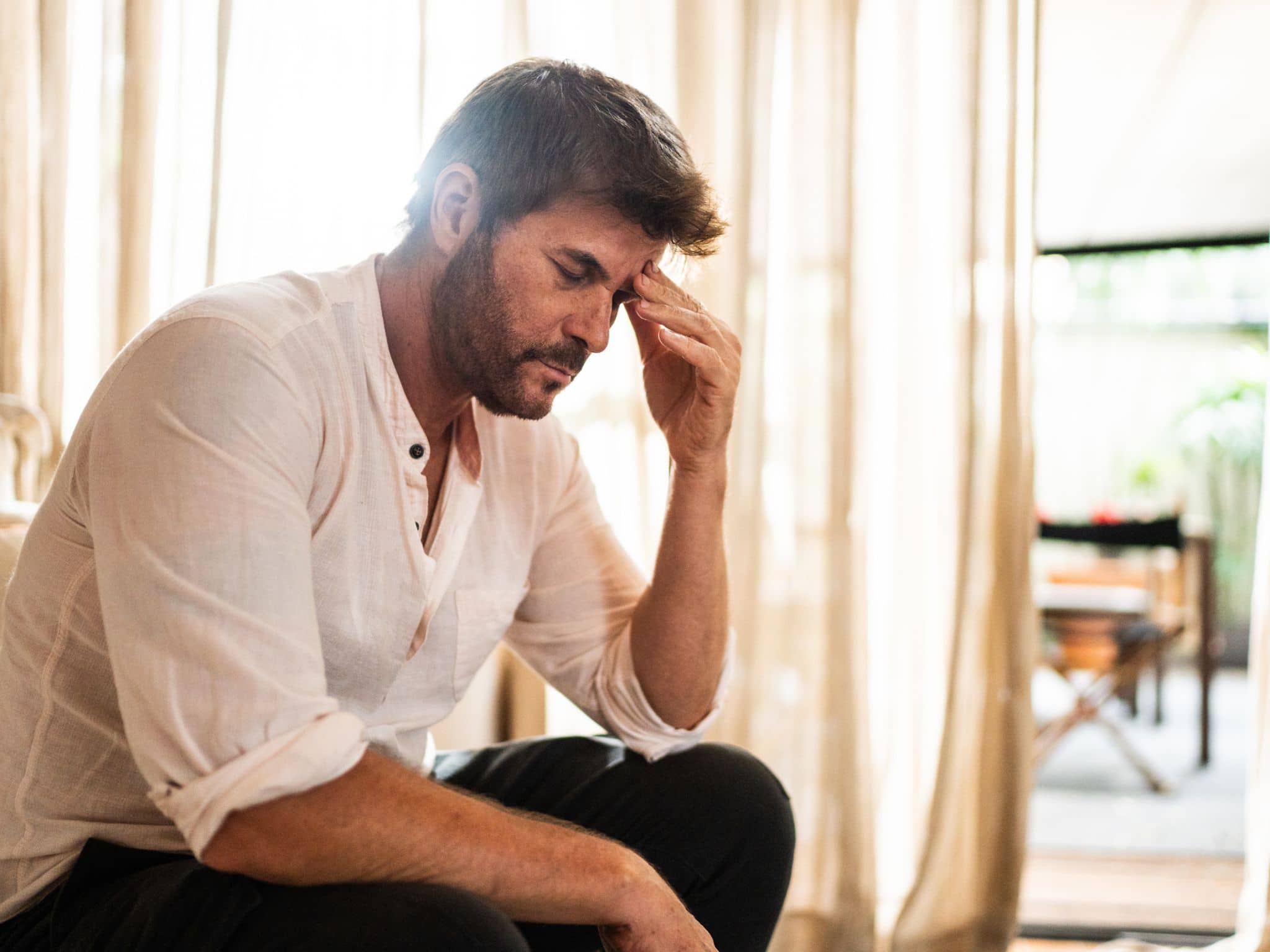 Ein Mann fasst sich an den Kopf, weil er Clusterkopfschmerzen hat.
