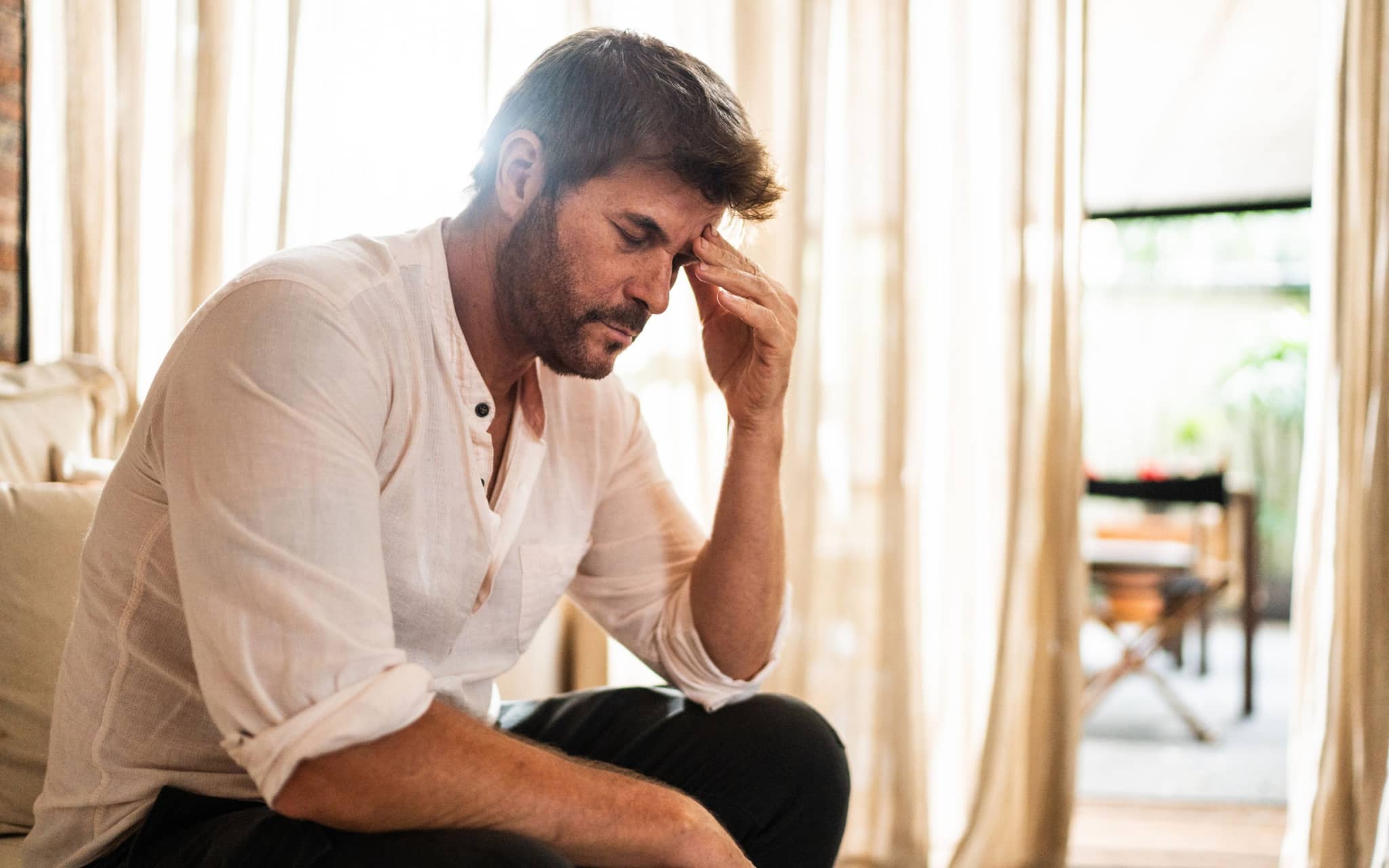 Ein Mann fasst sich an den Kopf, weil er Clusterkopfschmerzen hat.