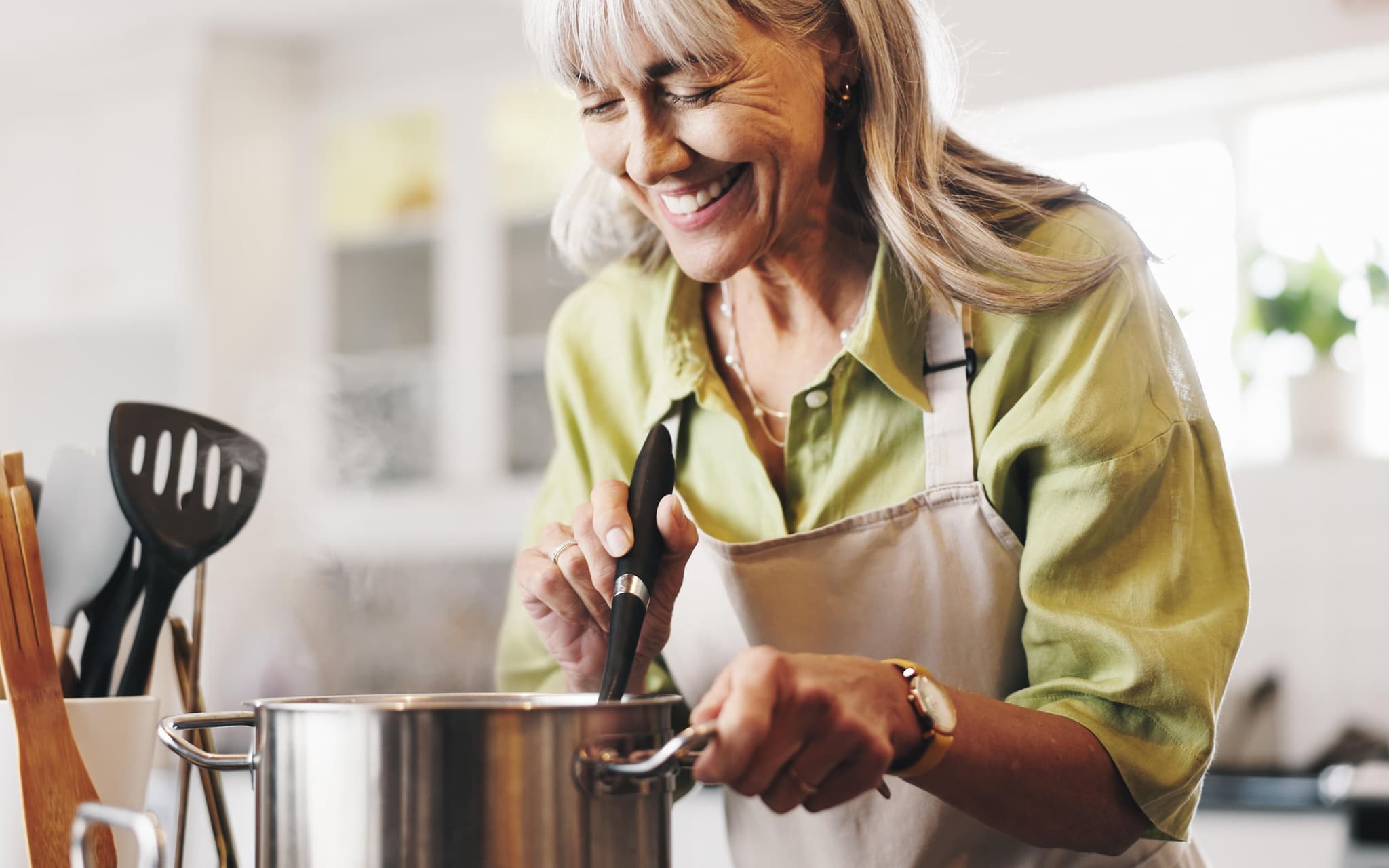 Rezept für gebratenen Weißkohl: Ältere Frau macht gebratenen Weißkohl mit Kabanossi in einem Topf.