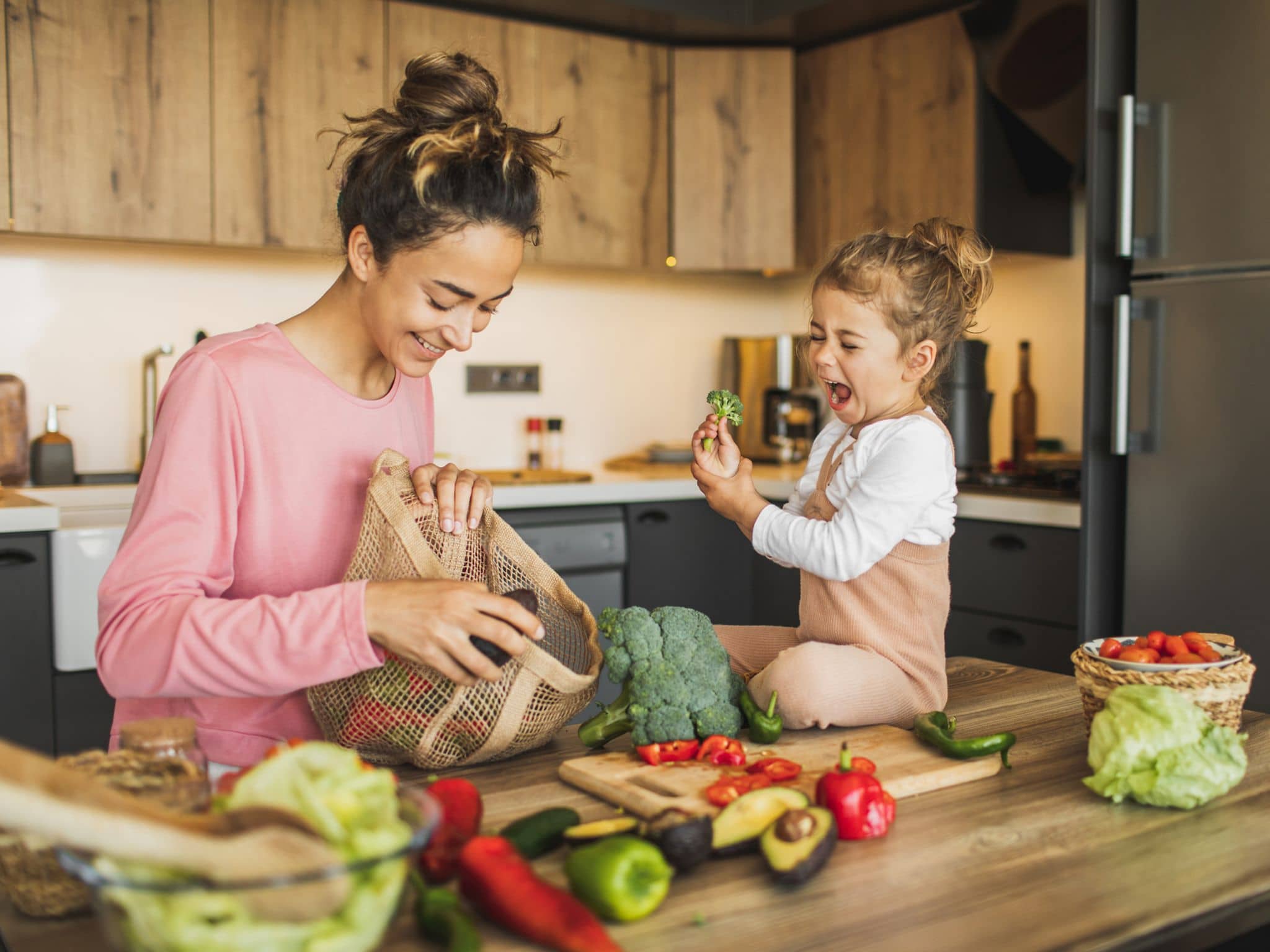 Frau und Kind mit Gemüse auf der Arbeitsplatte in der Küche