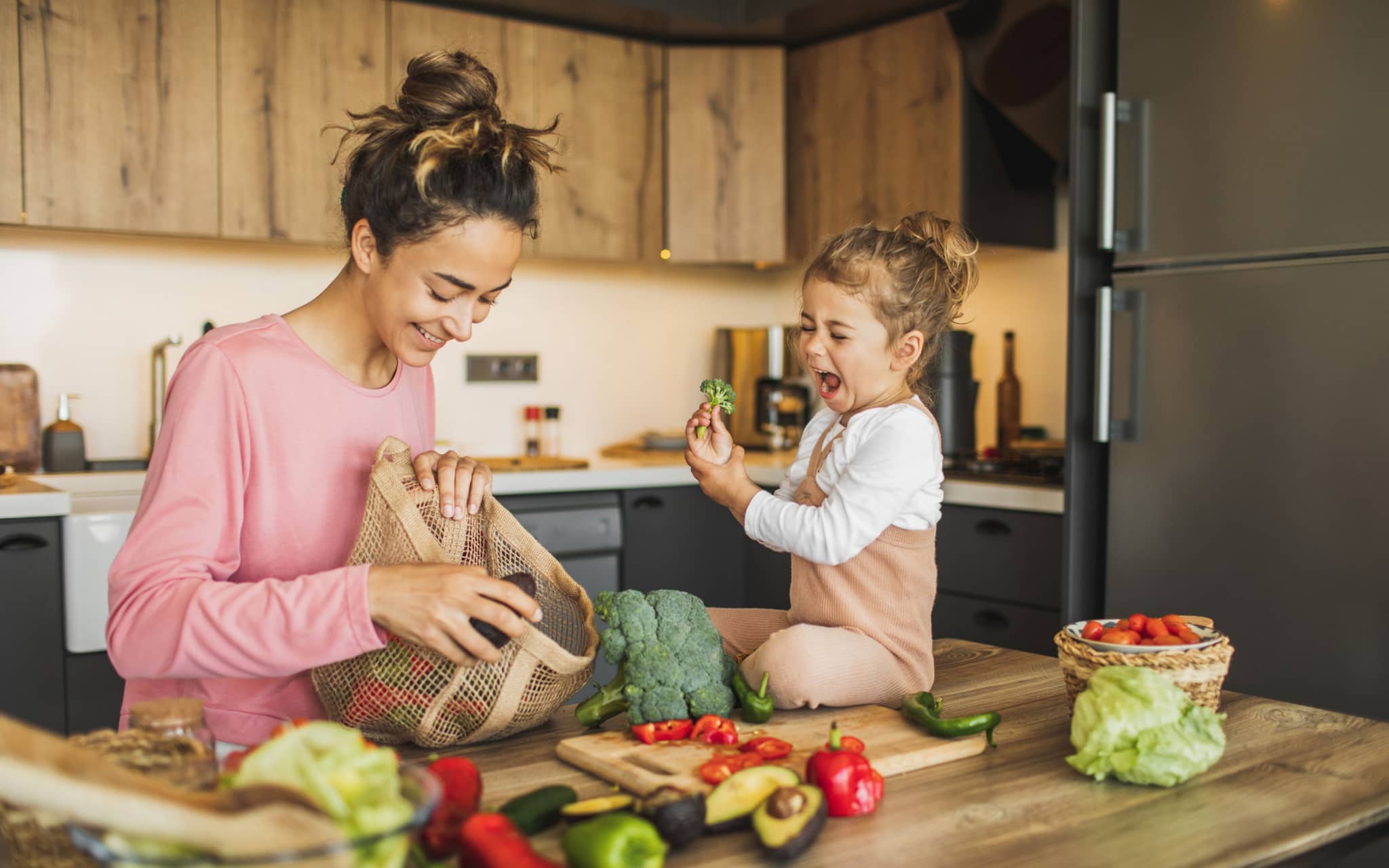 Frau und Kind mit Gemüse auf der Arbeitsplatte in der Küche
