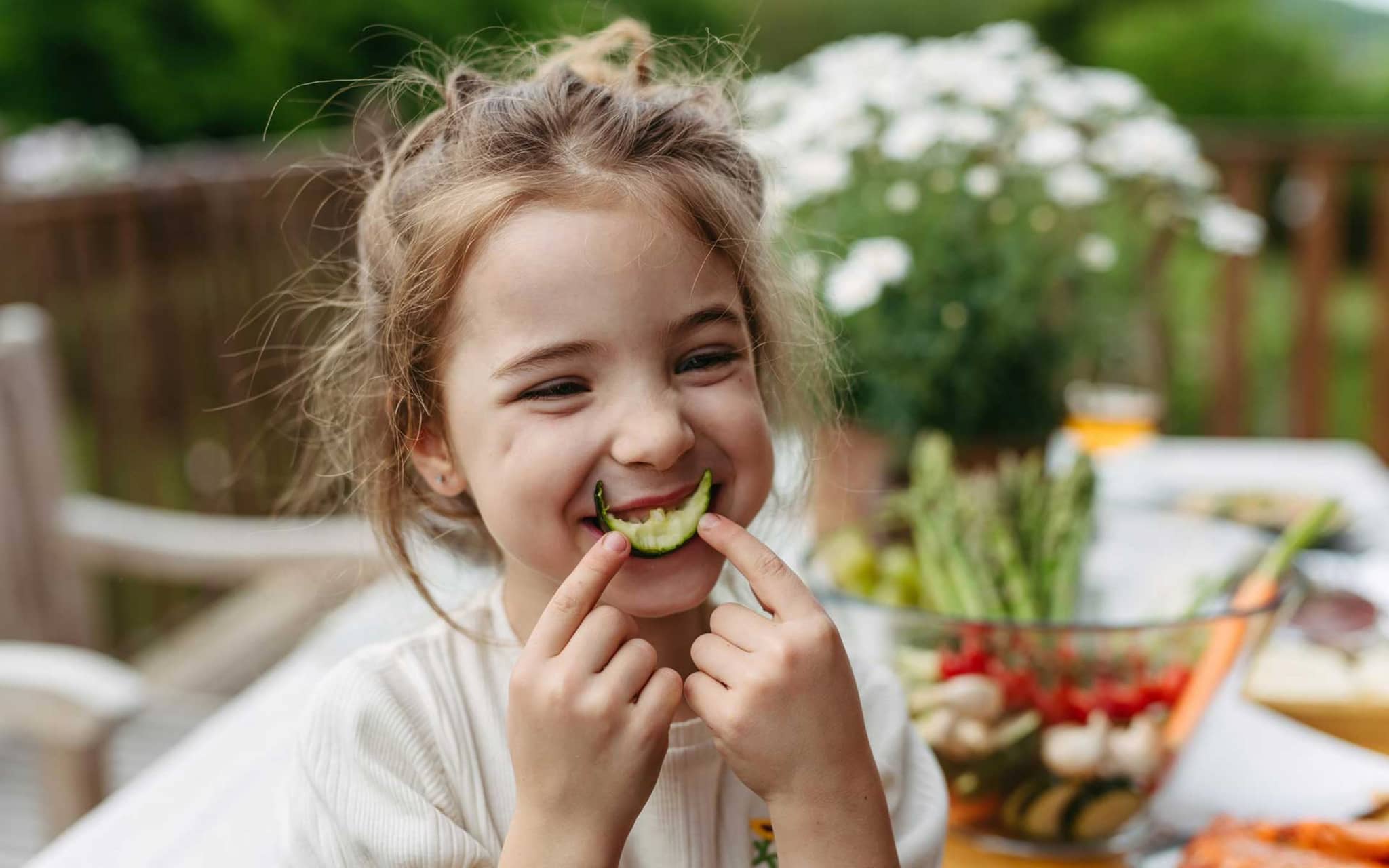 Mädchen hält sich angebissene Gurke vor den Mund