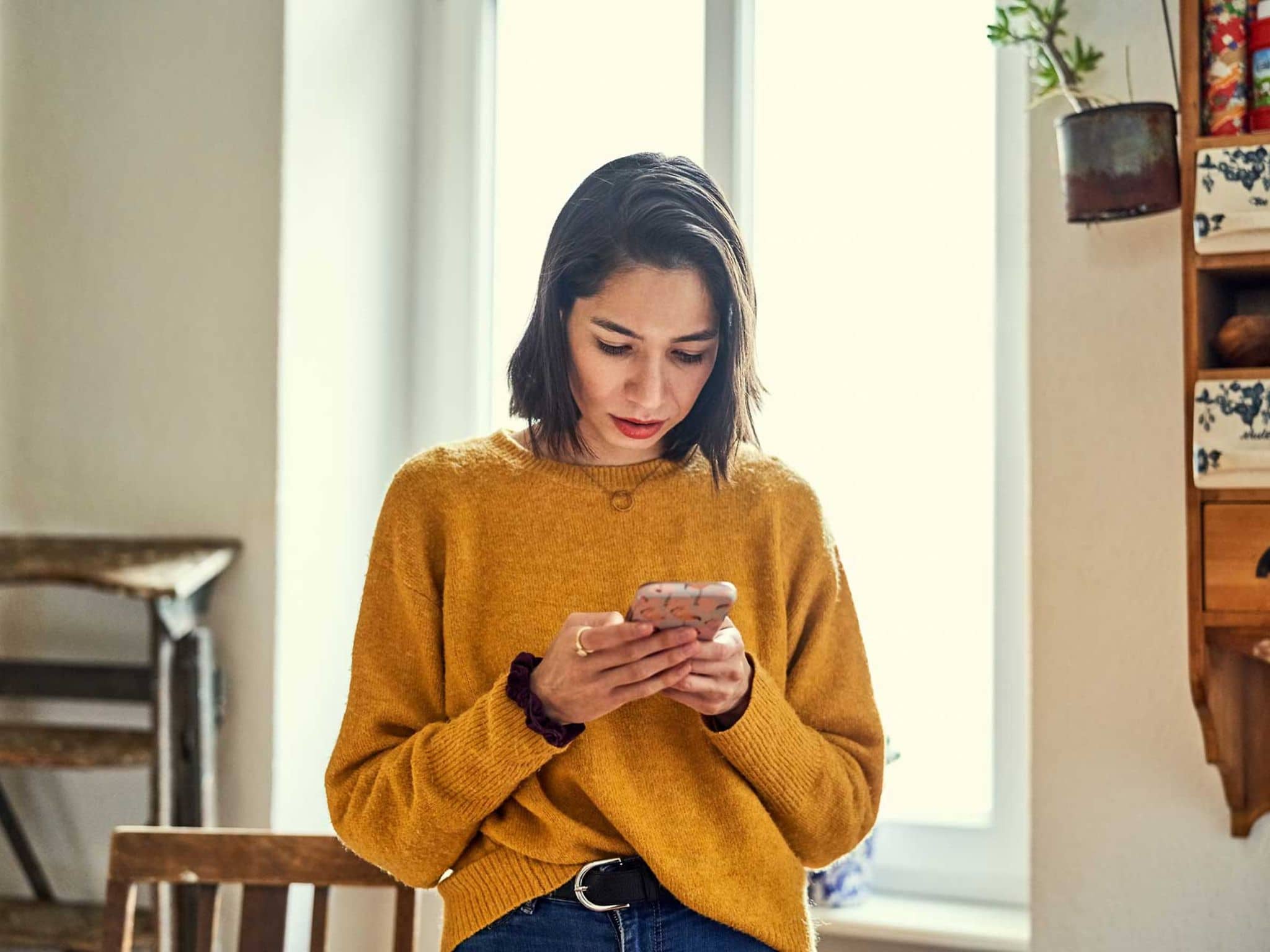 Junge Frau guckt stirnrunzelnd aufs Smartphone