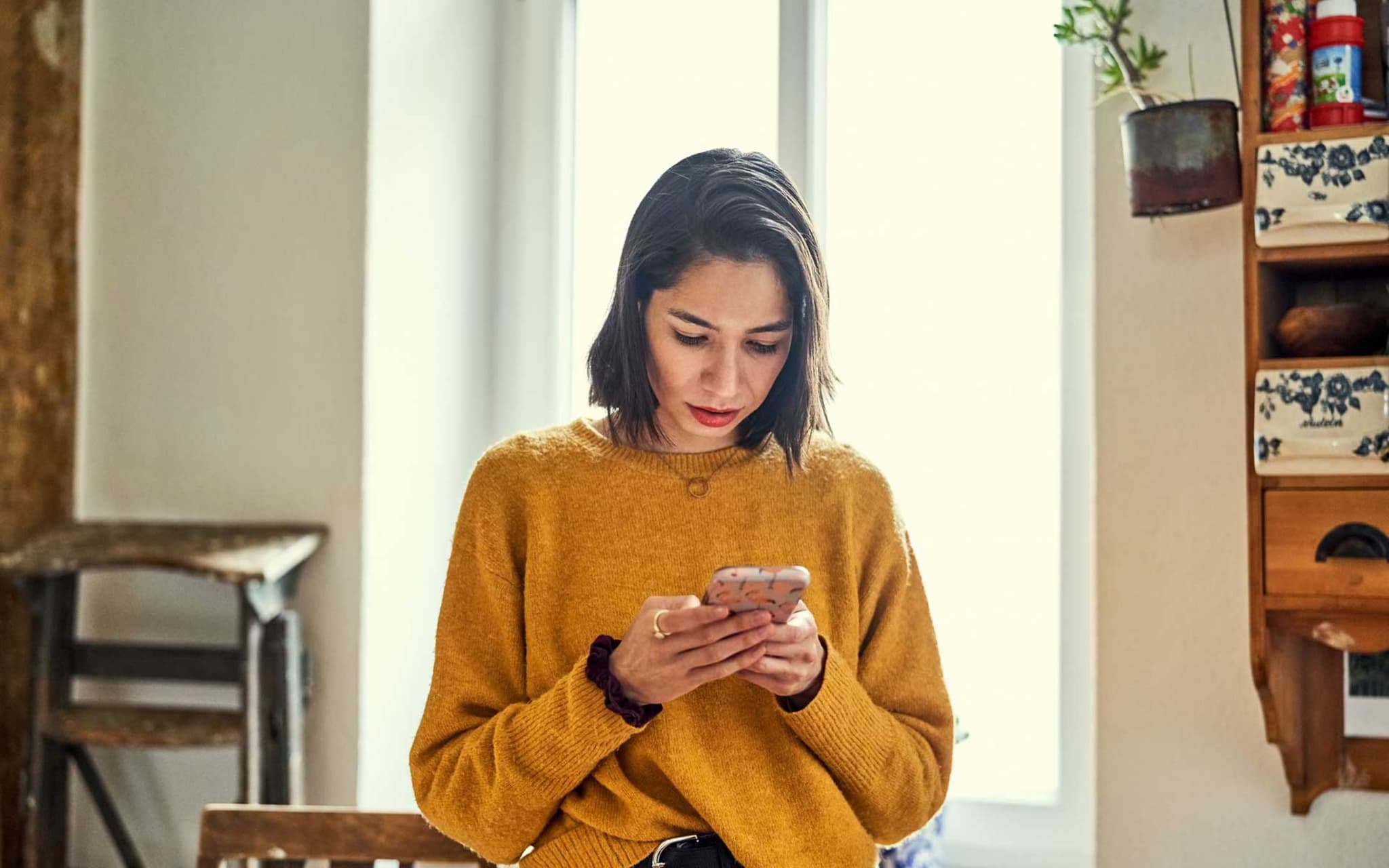 Junge Frau guckt stirnrunzelnd aufs Smartphone