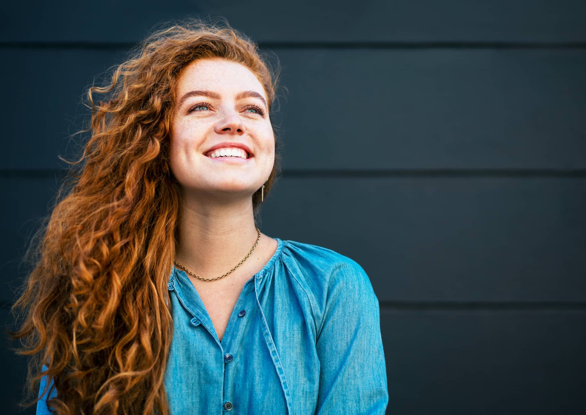 Bild: Frau mit roten Haaren schaut zuversichtlich und glücklich.