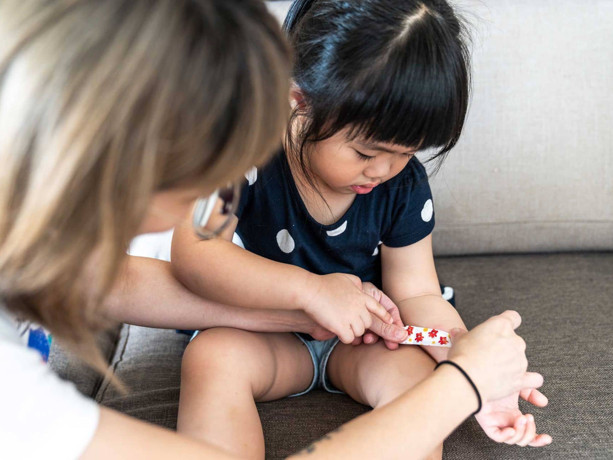 Mutter legt bei kleinem Mädchen ein Pflaster an