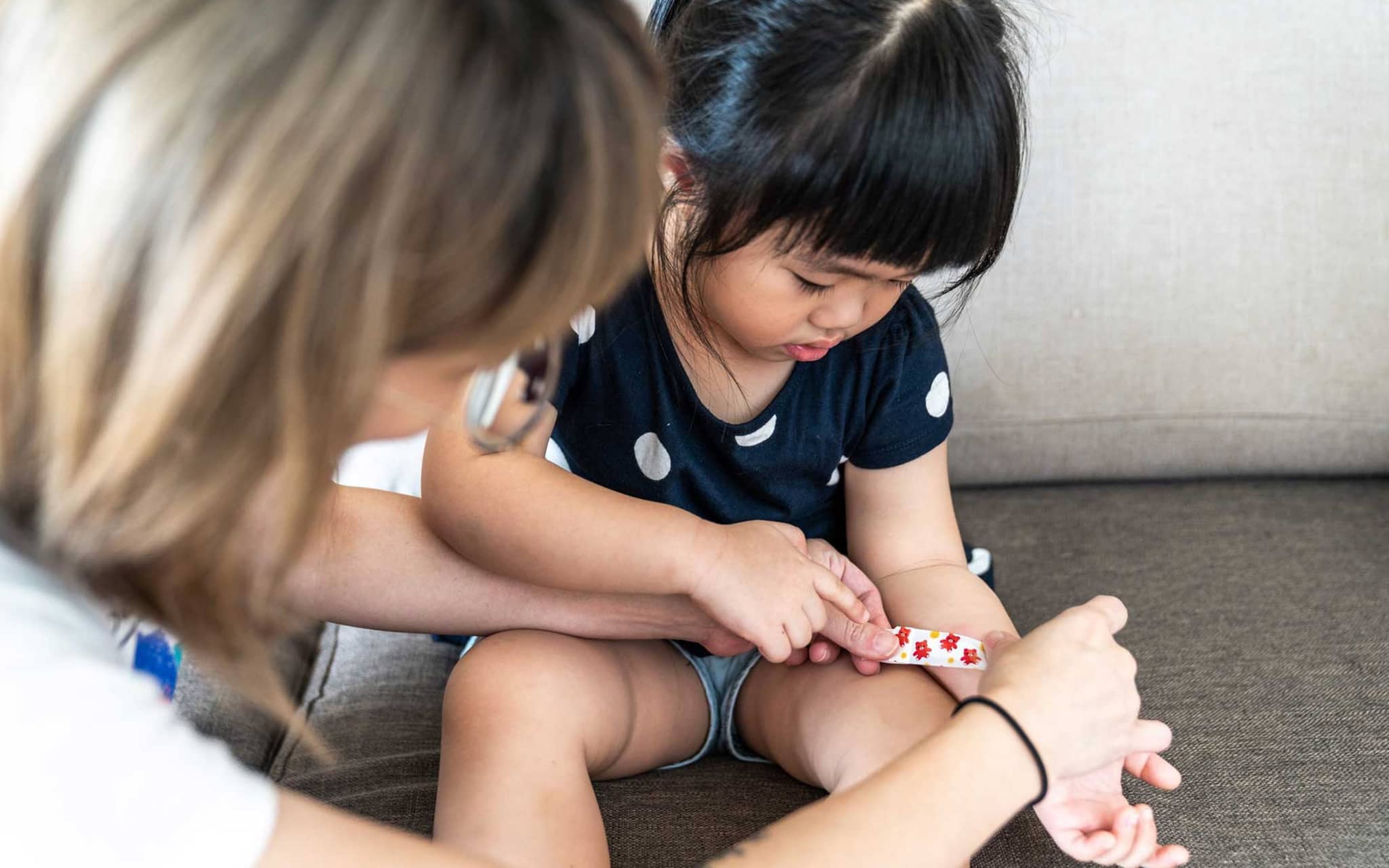 Mutter legt bei kleinem Mädchen ein Pflaster an