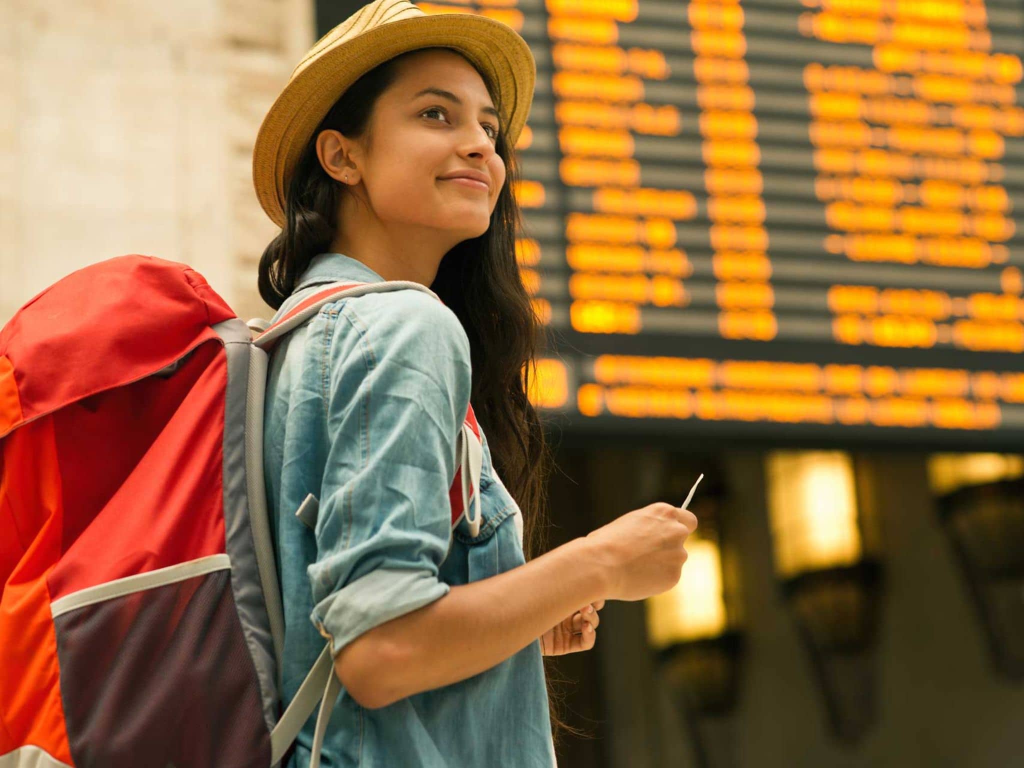 Junge Frau mit Reiserucksack in einer Bahnhofshalle