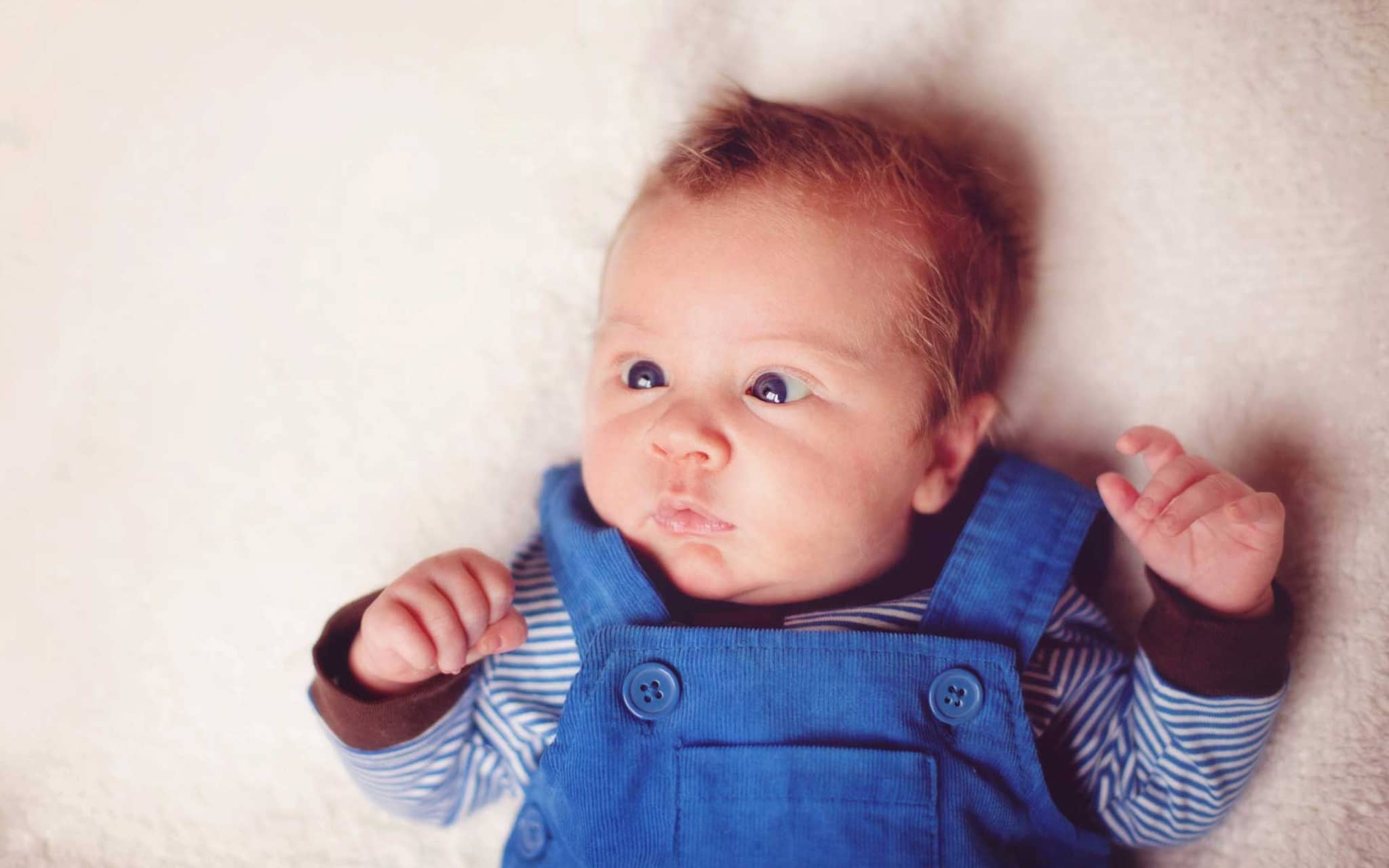 Ein schielendes Baby liegt im Bett